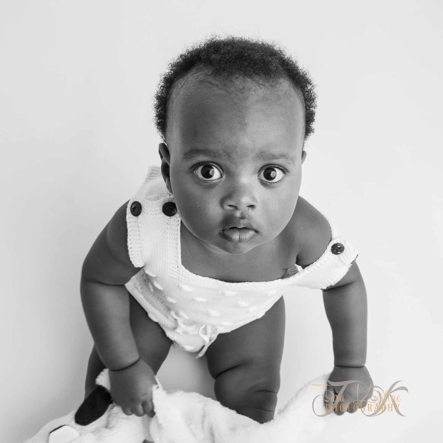 Baby in white dress during professional black and white portrait session.
