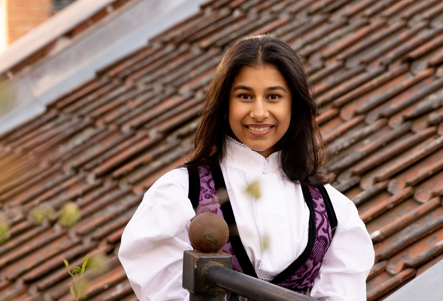 Person wearing folk dress poses against brick wall with natural lighting.