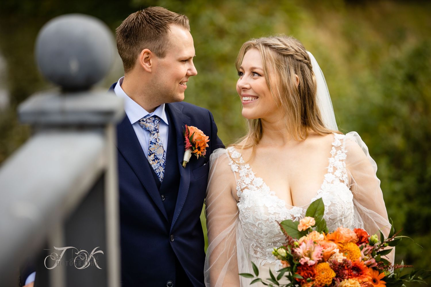 A couple shares a tender moment in a garden setting with autumn colors.