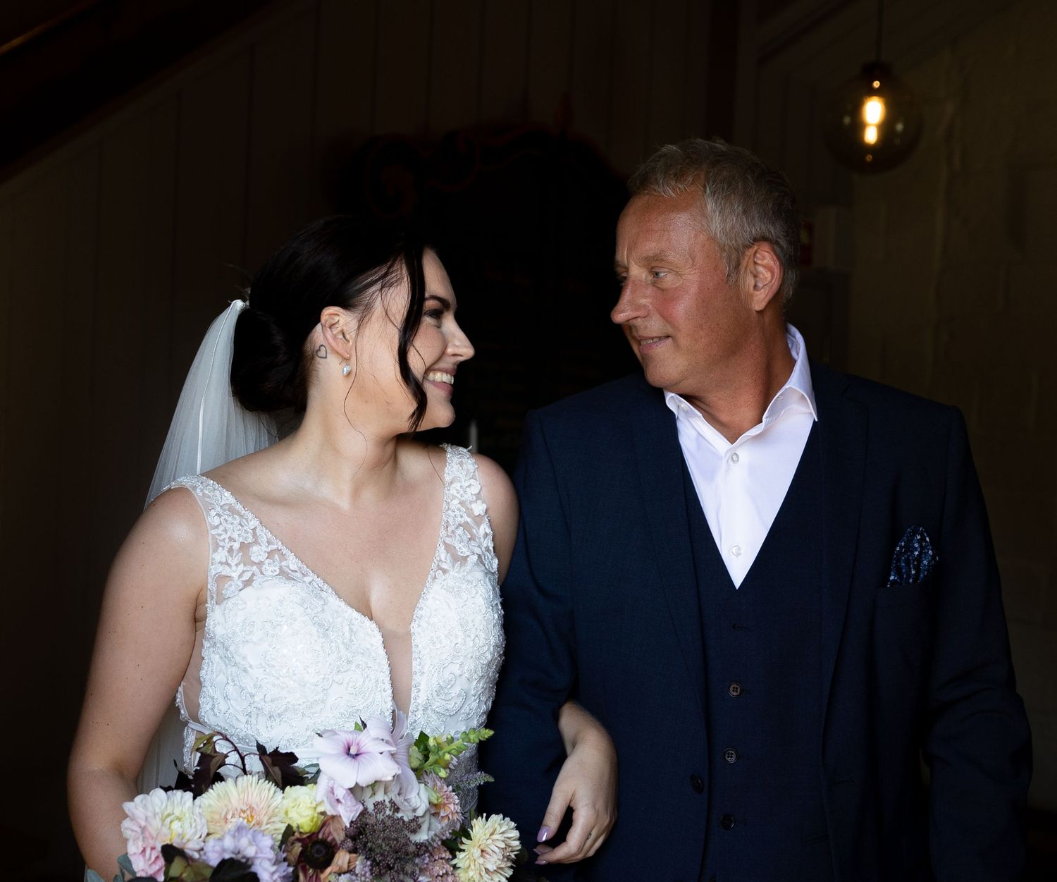 A touching candid moment between two wedding guests in formal attire sharing a laugh.
