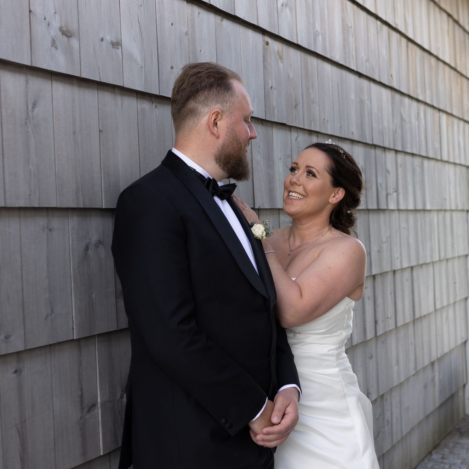 A couple shares an intimate moment against a grey wall during their wedding.