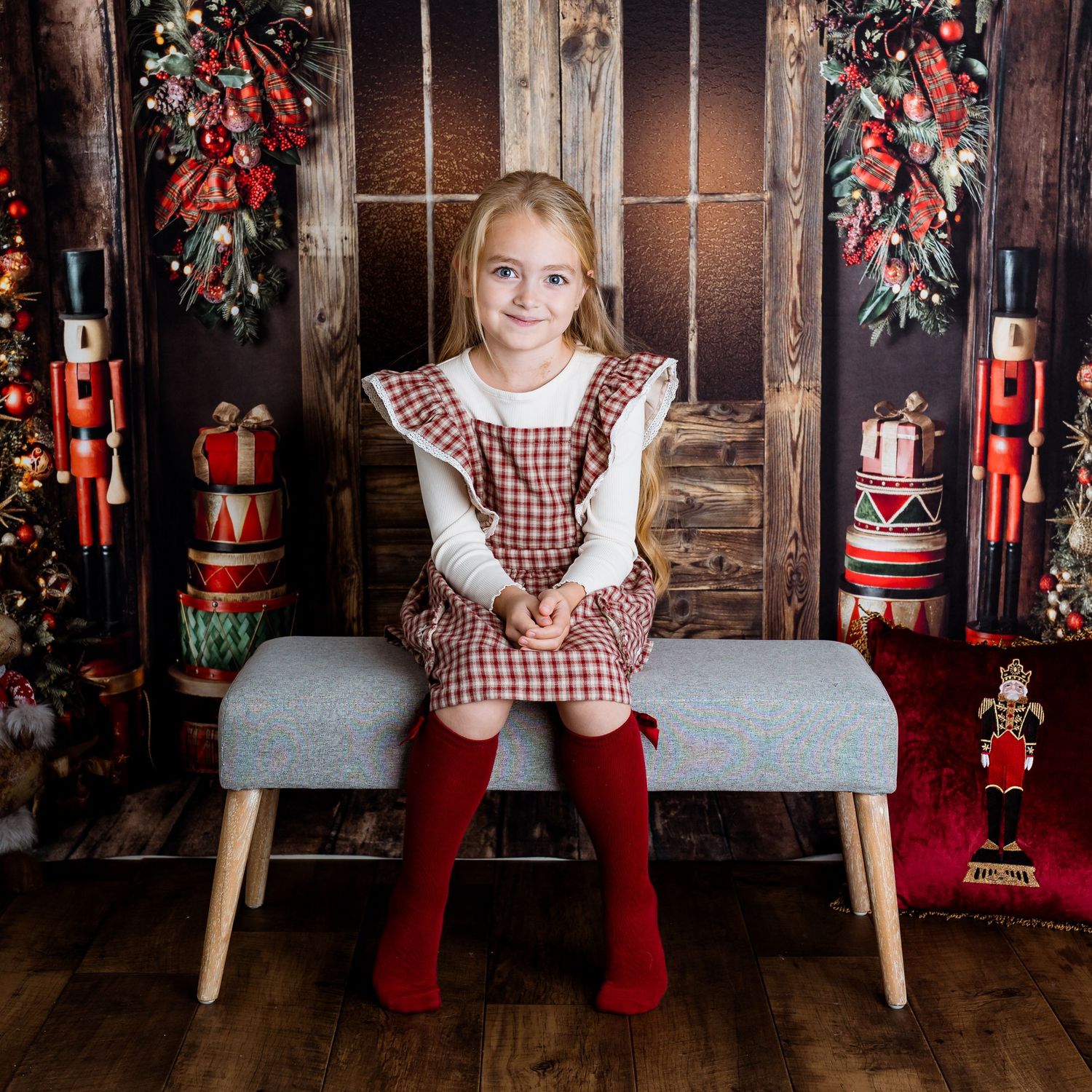 Holiday portraits featuring red and white checkered dress against Christmas decorated backdrop.