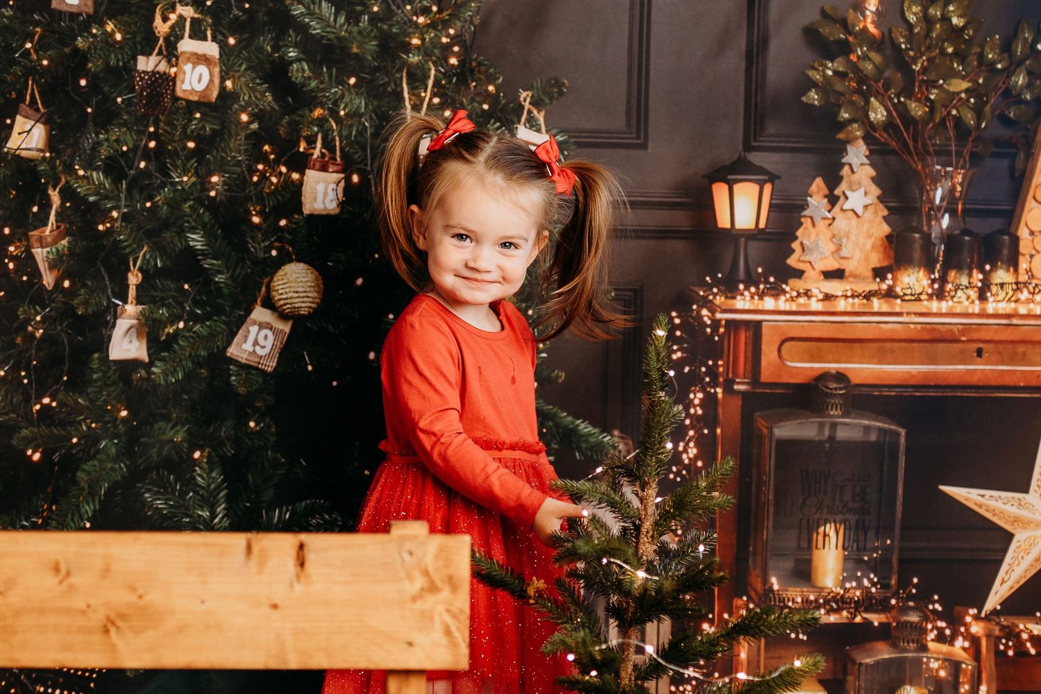 Christmas photo setup with decorated tree, wooden elements and warm lighting.