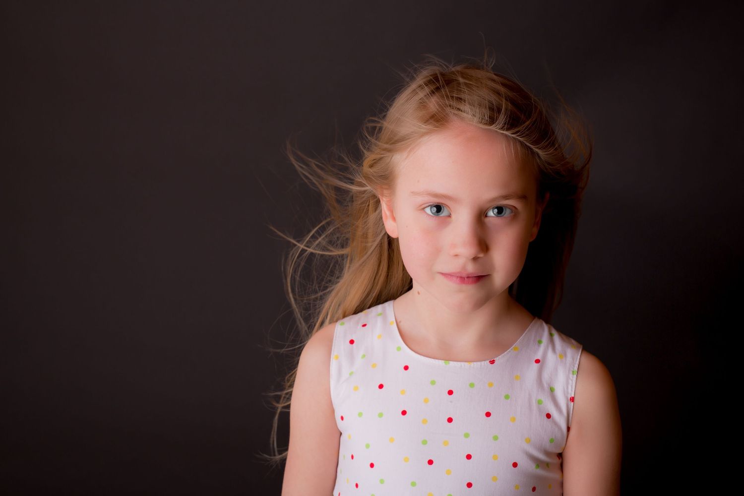 Portrait against dark background wearing polka dot dress.