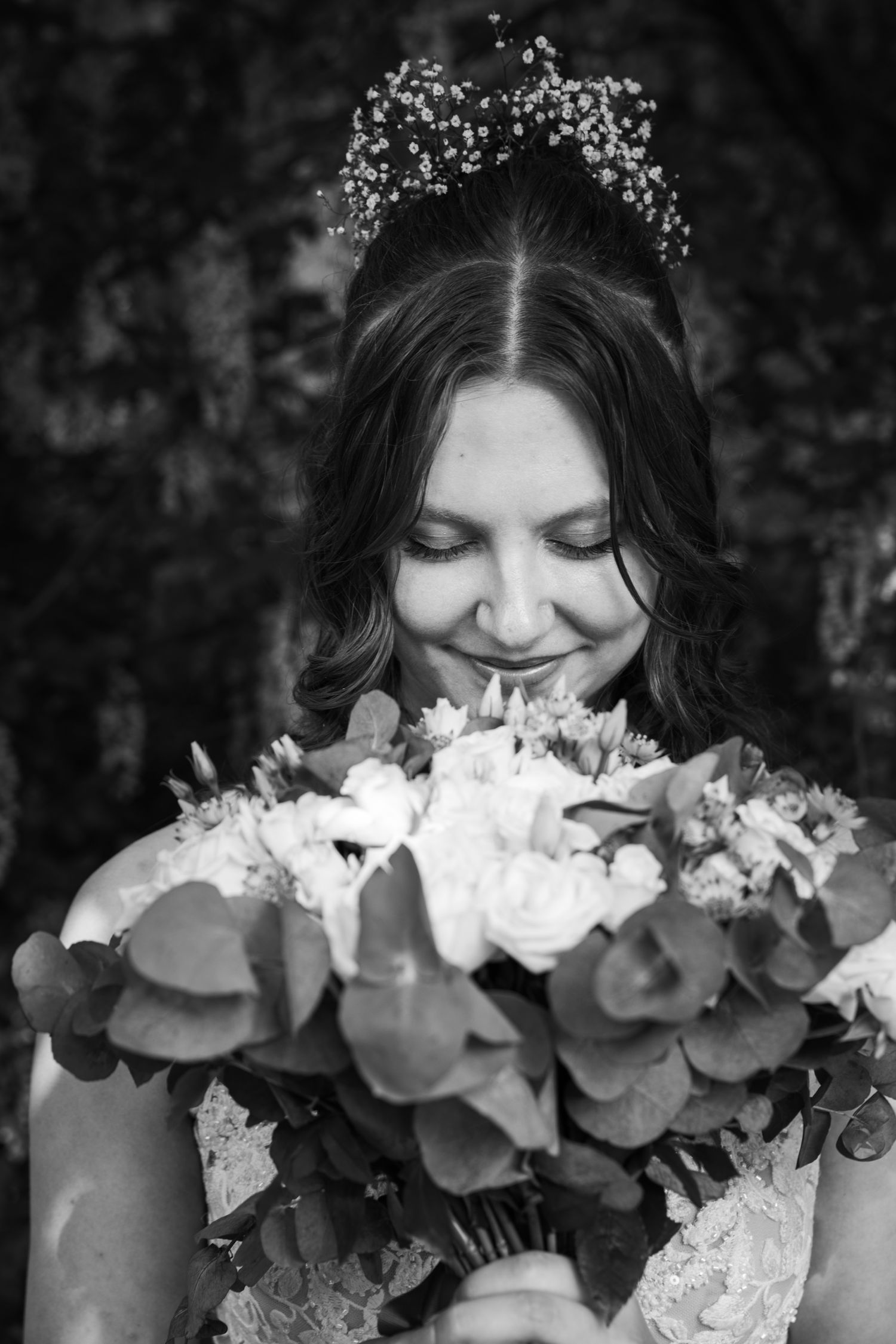 Black and white portrait of bride smelling elegant white floral bouquet.