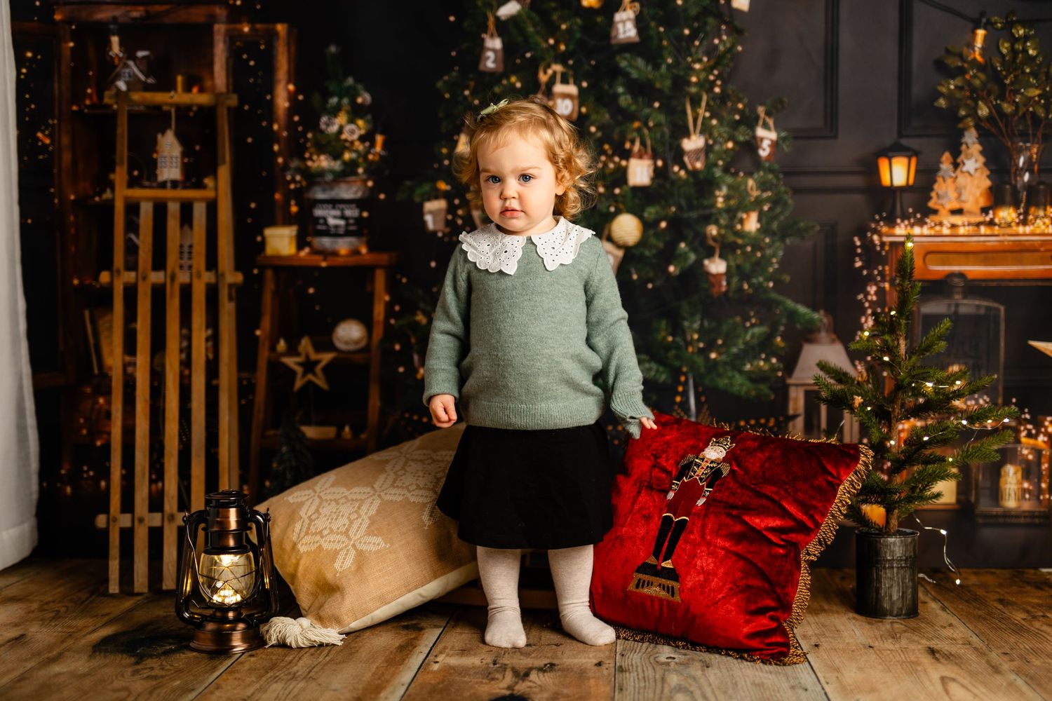 Holiday portrait with Christmas tree backdrop featuring vintage wooden sled and festive decor.
