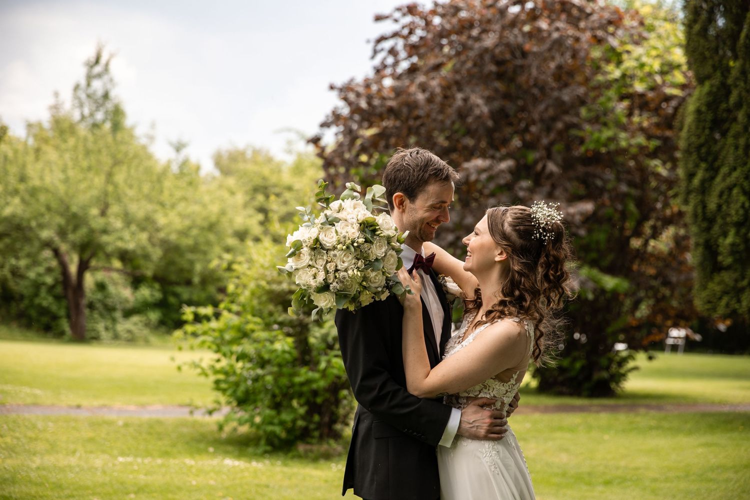 Wedding couple embracing in a lush garden setting during golden hour.