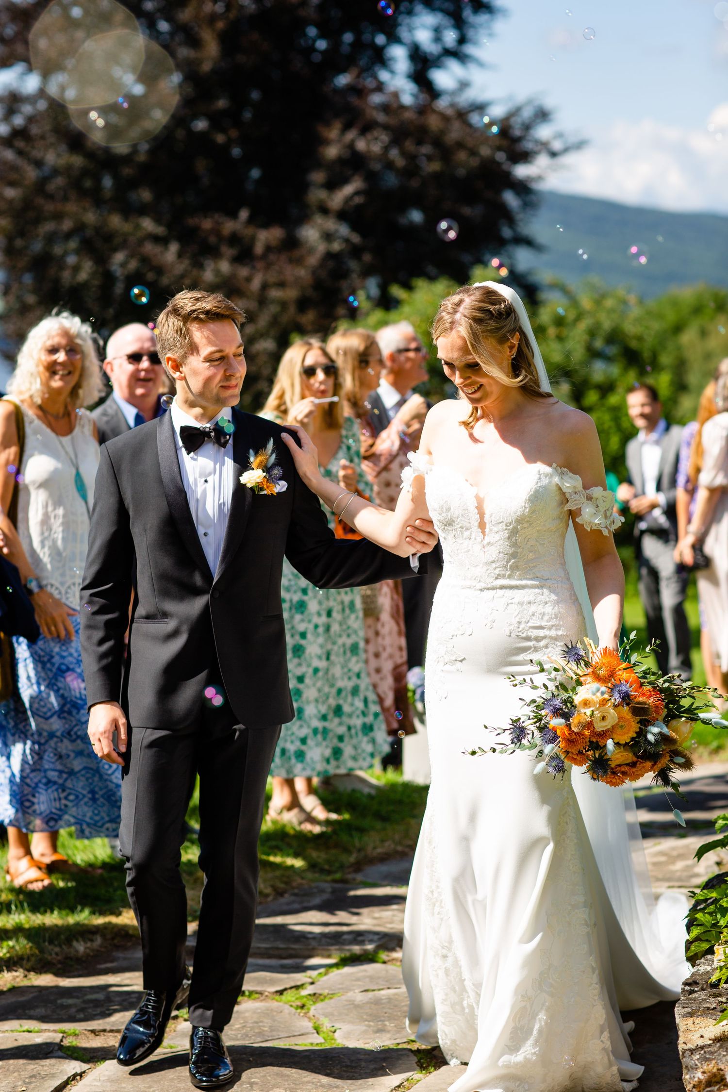 Wedding party walking outdoors while guests throw confetti in celebration.