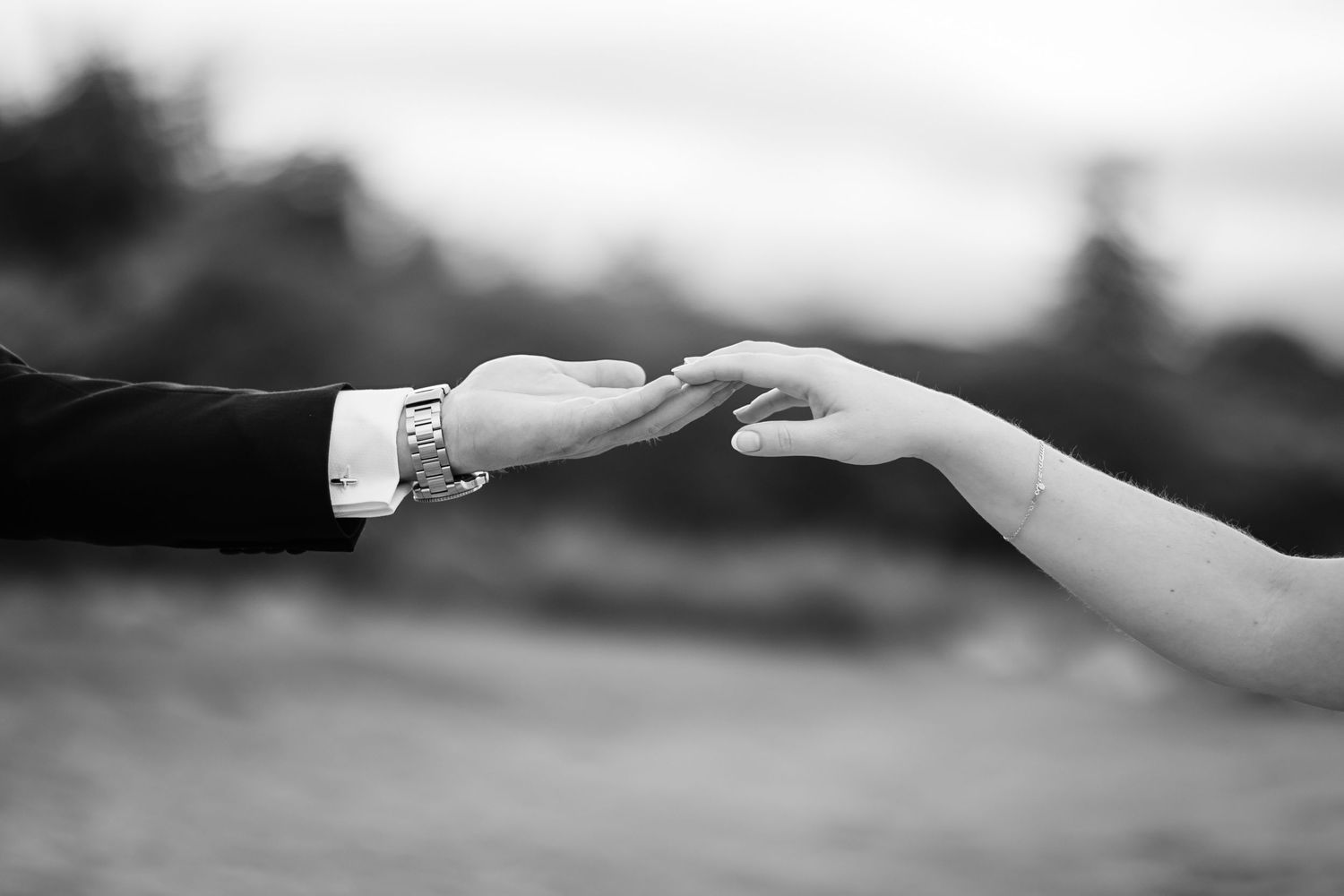 Hands reaching towards each other in a romantic black and white photo.