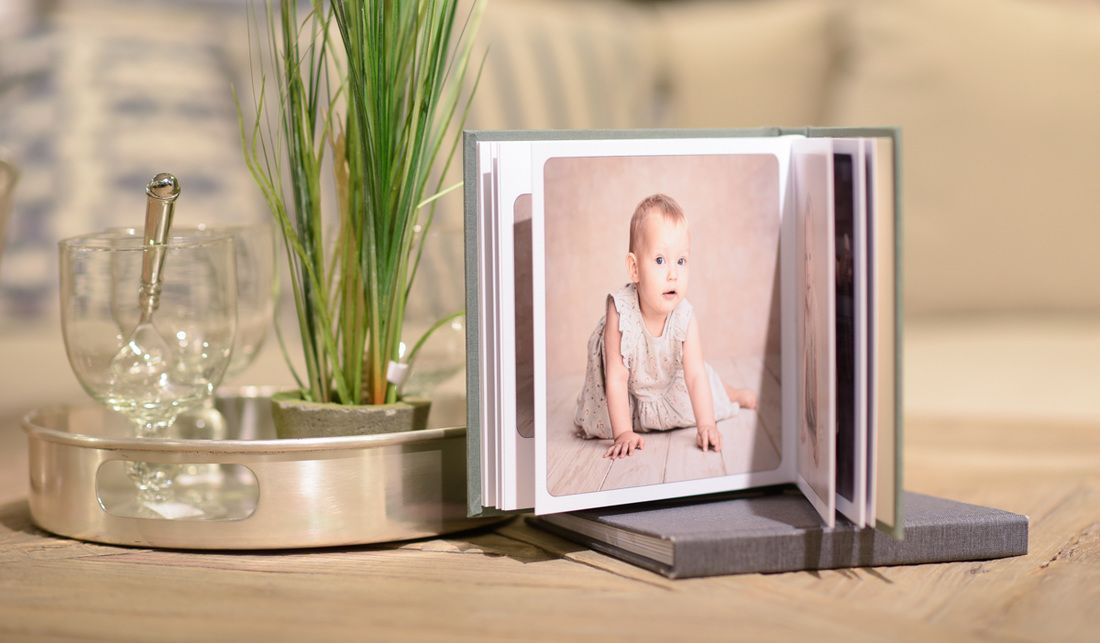 Photo album display with decorative grass in glass vase.
