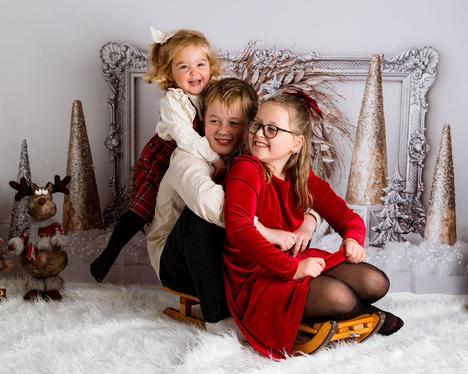 Holiday portrait session with children against winter wonderland backdrop and decorations.