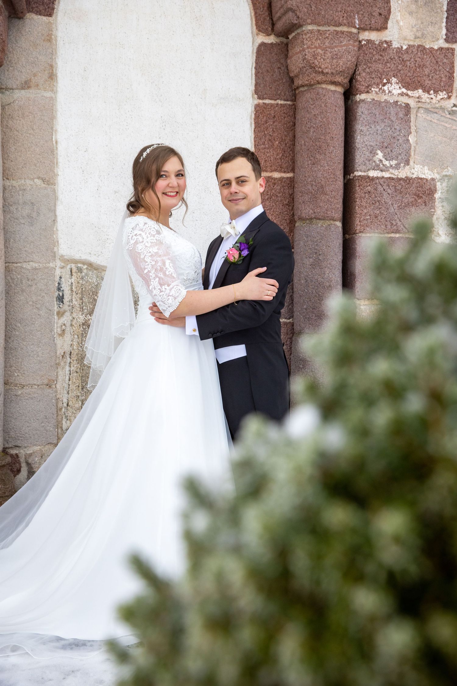 Wedding couple poses in front of a red chevron door with bride holding pink bouquet.