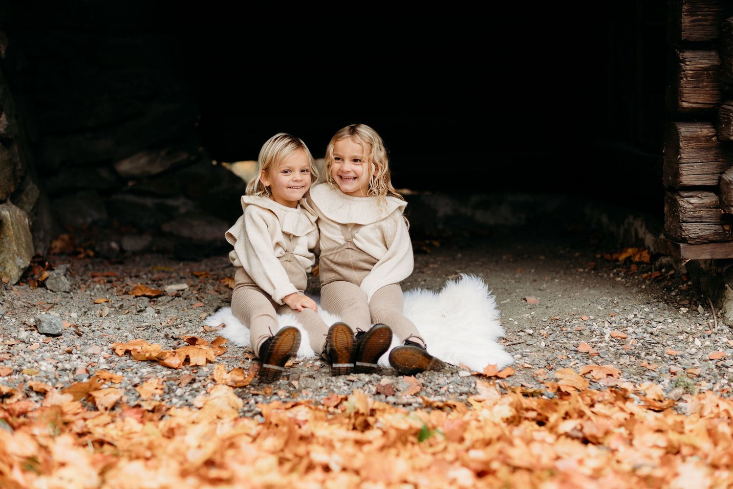 Children playing in autumn leaves during an outdoor photo session.
