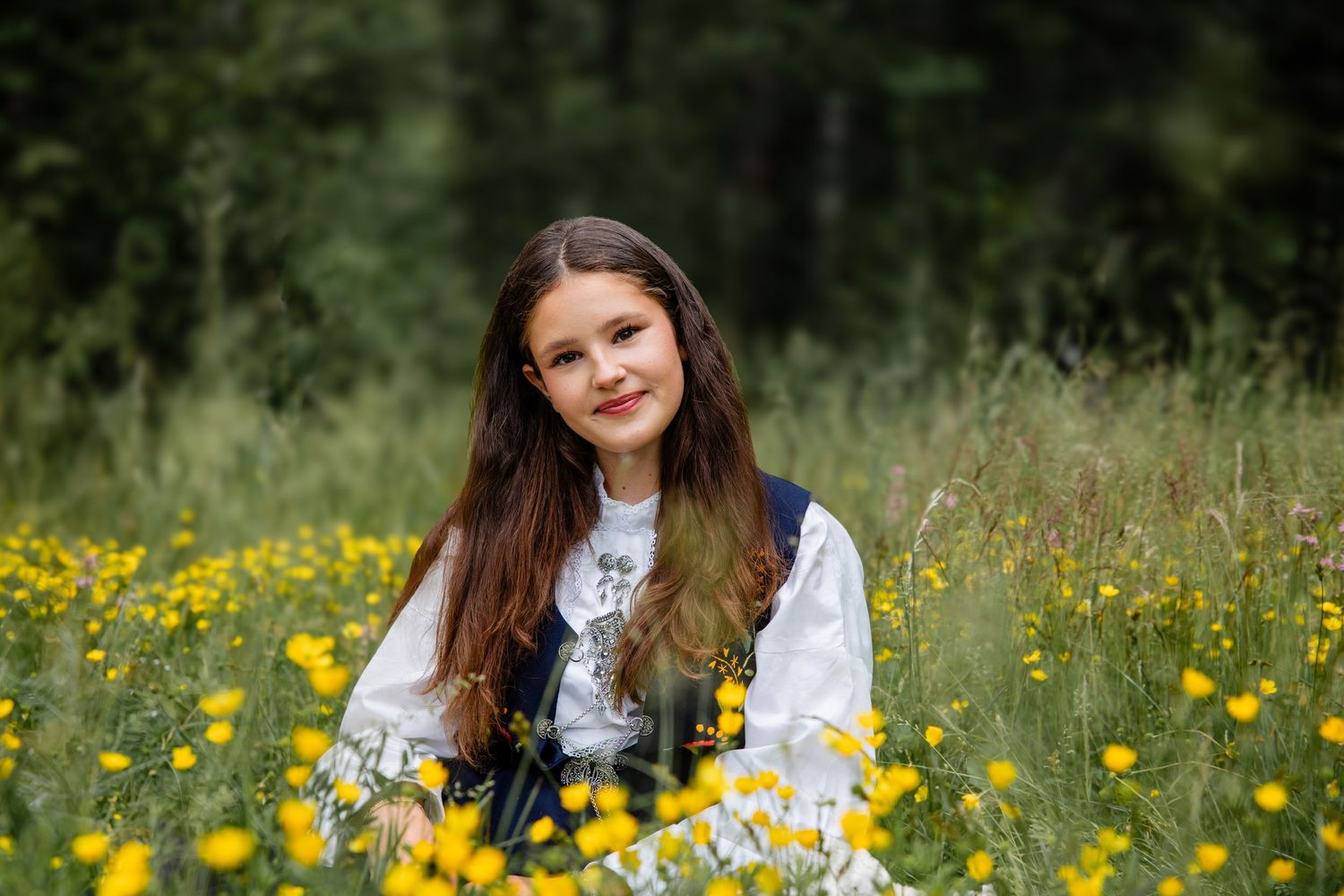 A person sits in a vibrant meadow filled with yellow wildflowers on a sunny summer day.