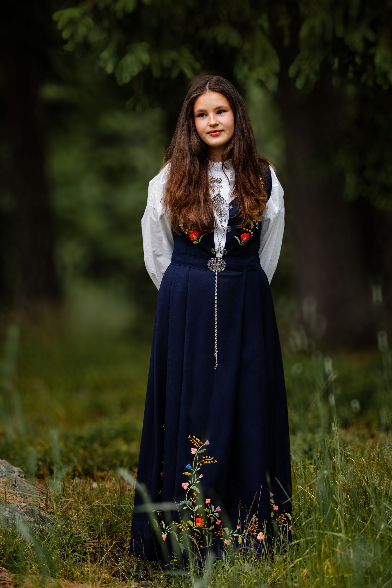 Four artistic photos show a navy blue dress with embroidered floral details against a natural outdoor background.