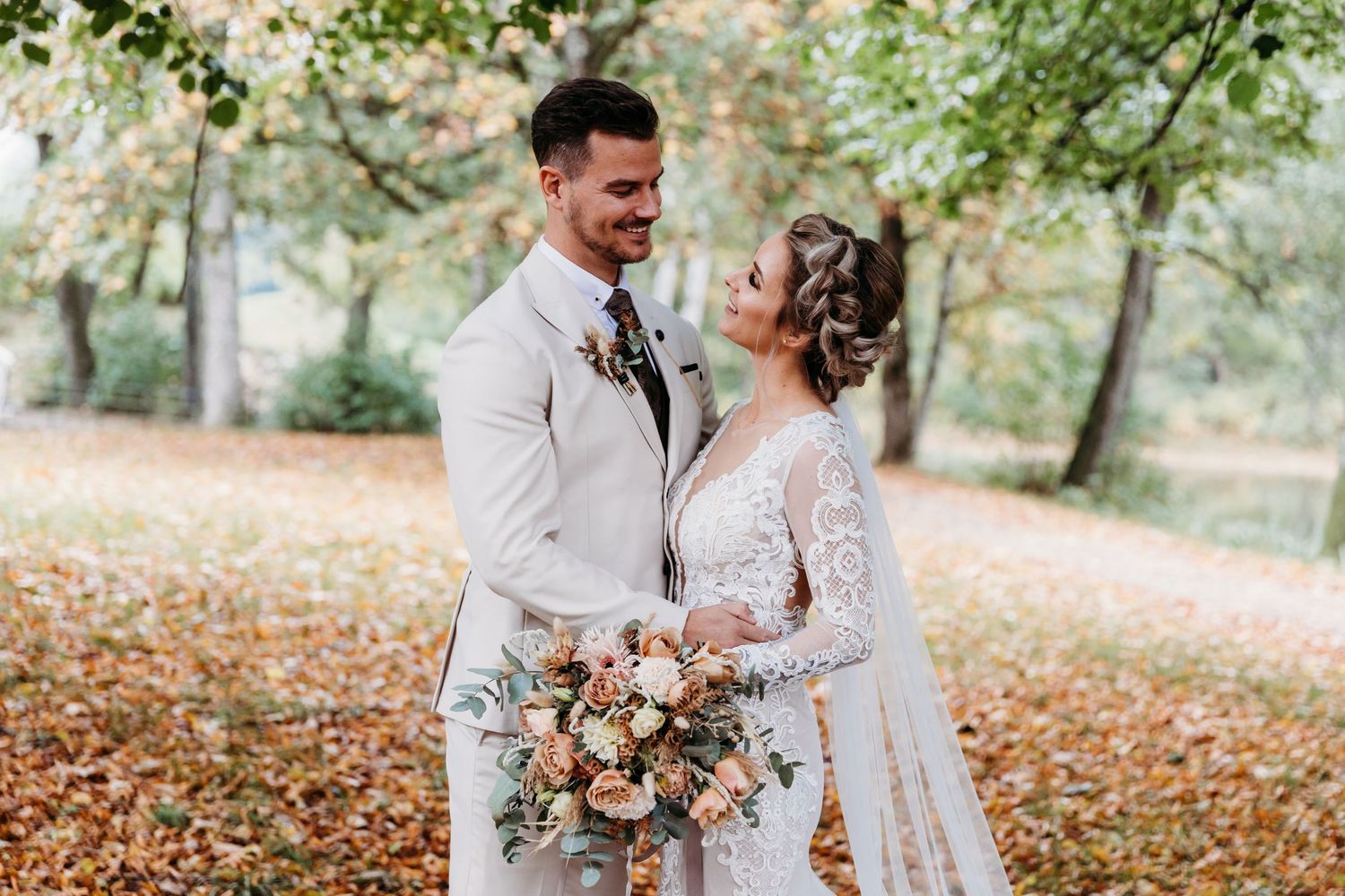Autumn wedding photos in a park with fallen leaves and natural scenery.