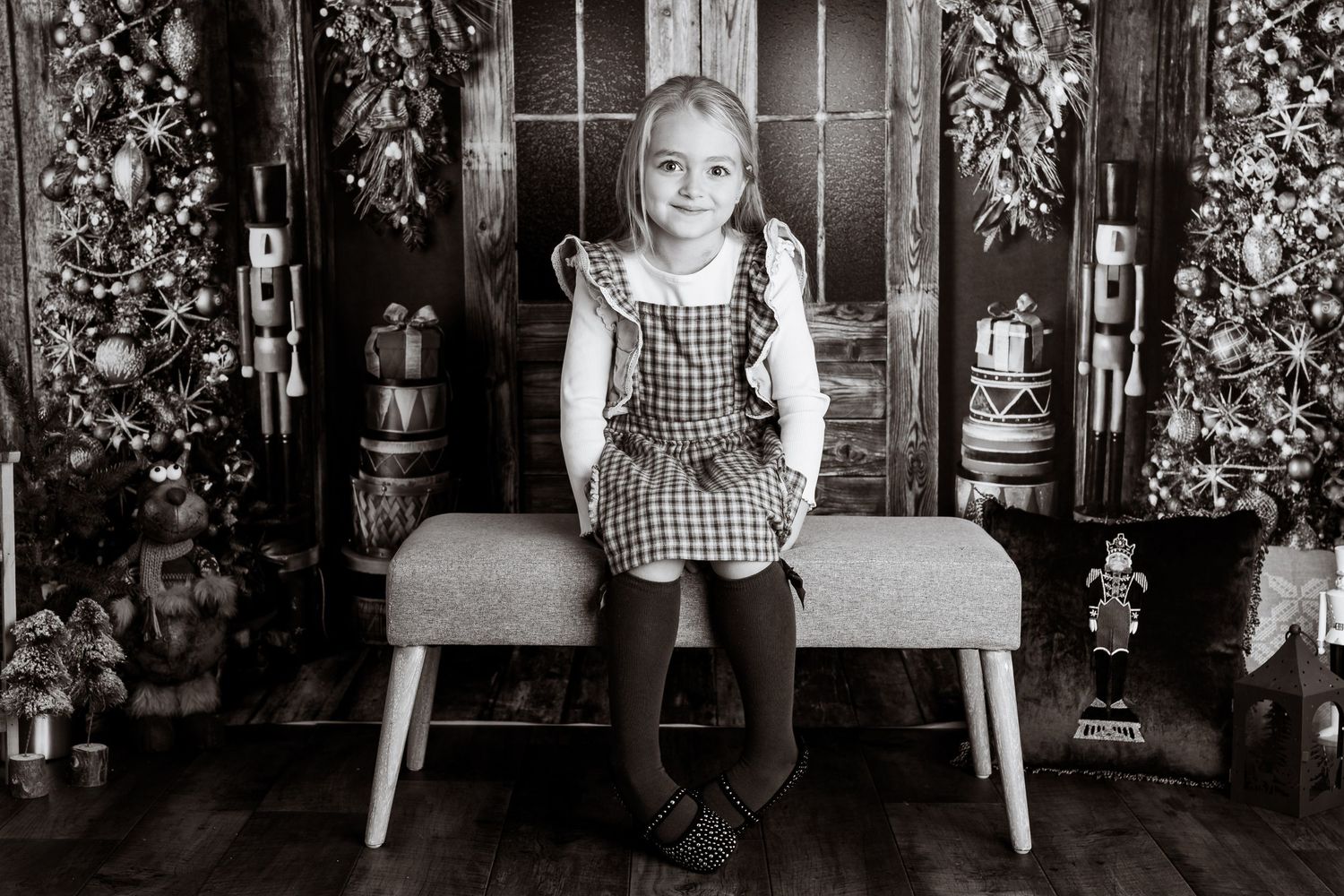 Black and white family portrait series with Christmas decorations and wooden chairs.