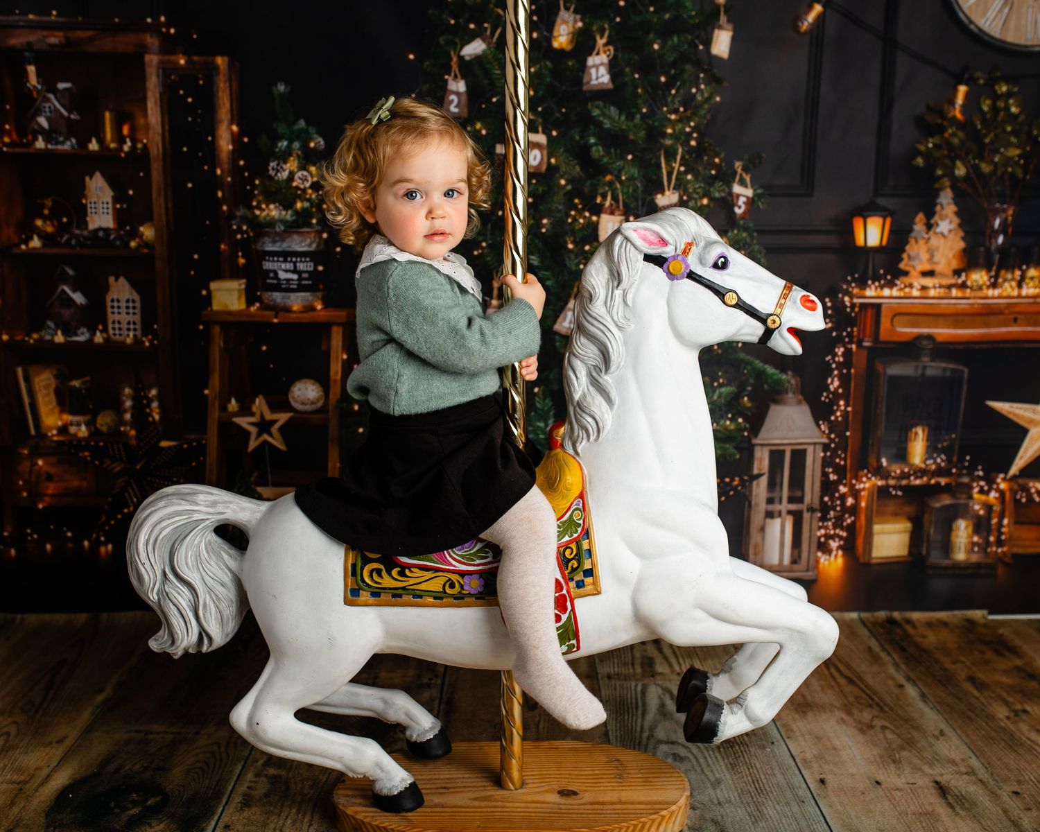 Carousel horse photo session with Christmas lights and decorative lanterns in dark setting.