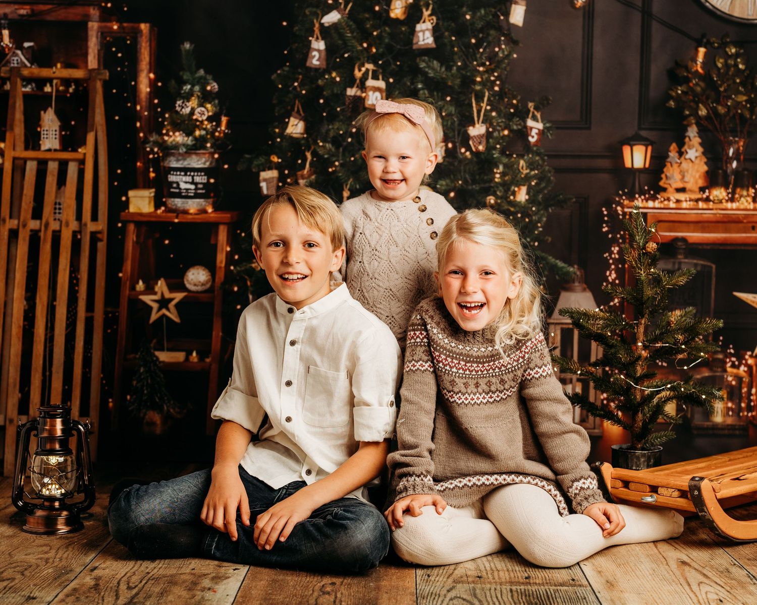 Festive family photoshoot with Christmas tree and rustic wooden decorations.