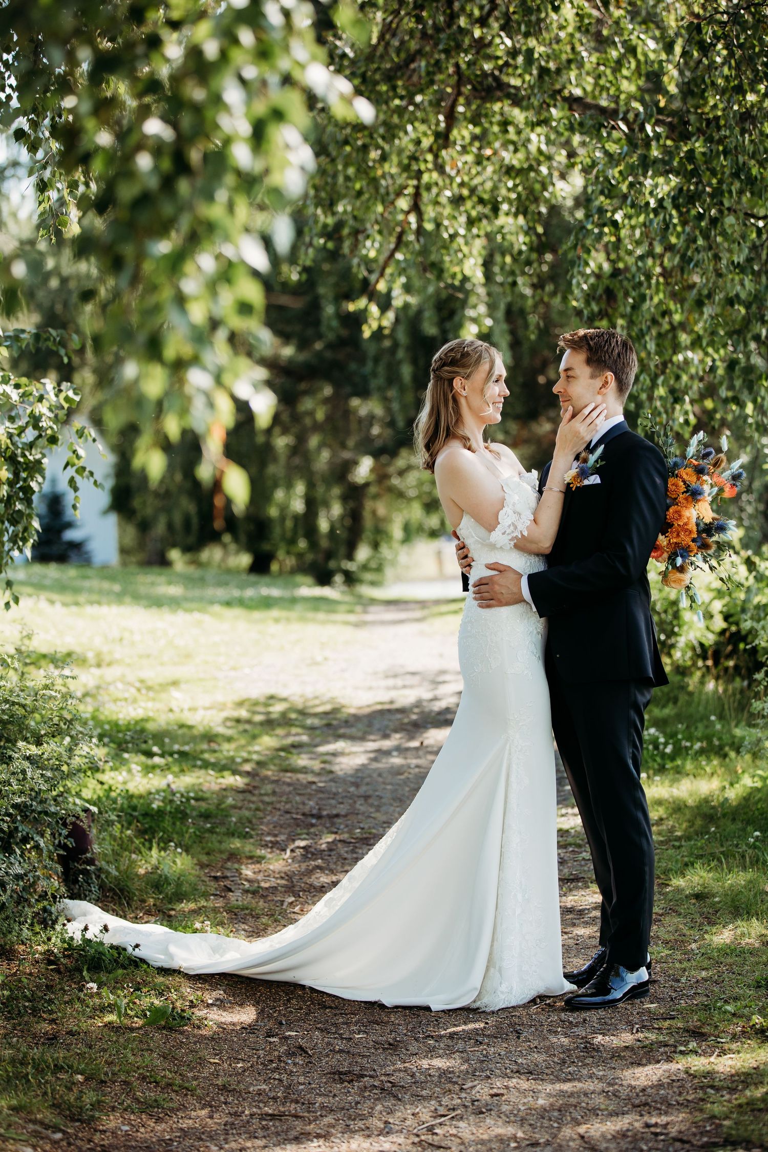 Wedding couple portraits under green trees with flowing white dress.