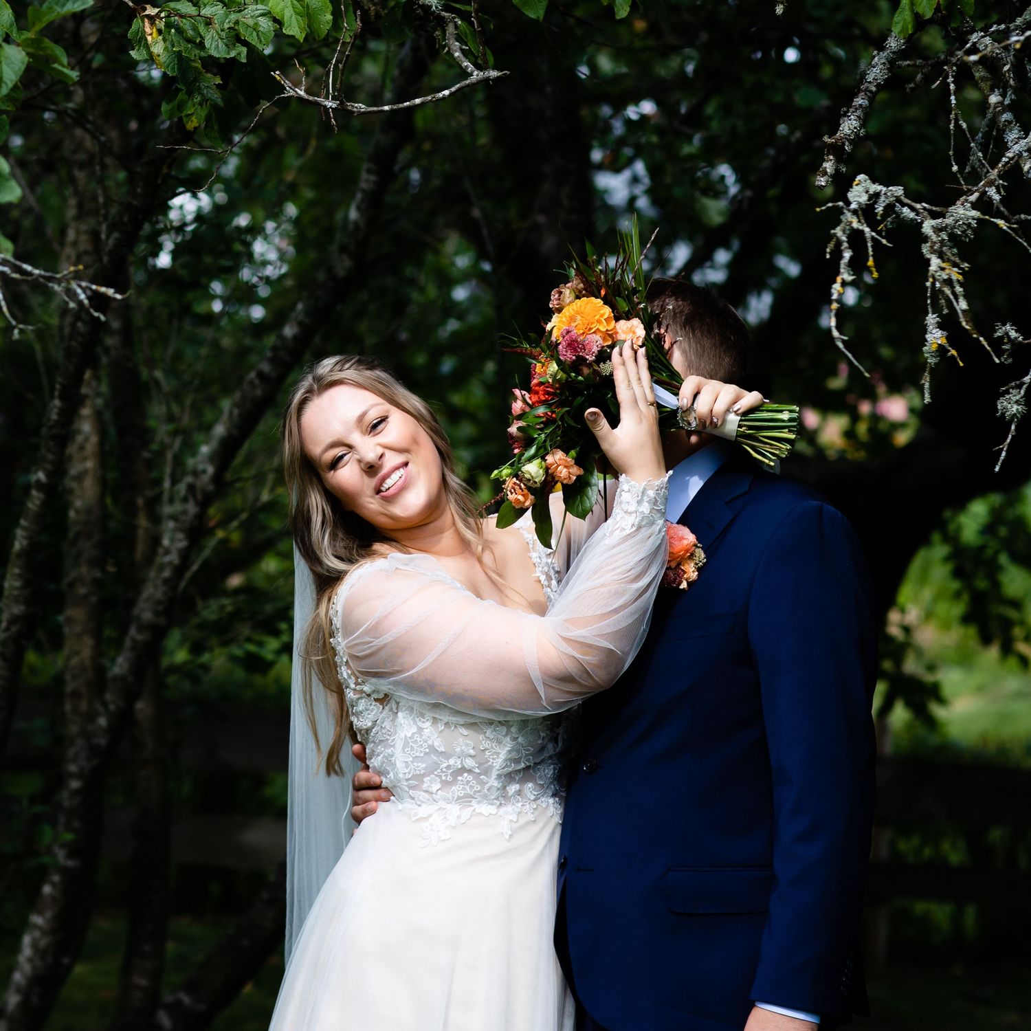 A couple embraces in a wooded outdoor setting during their wedding.