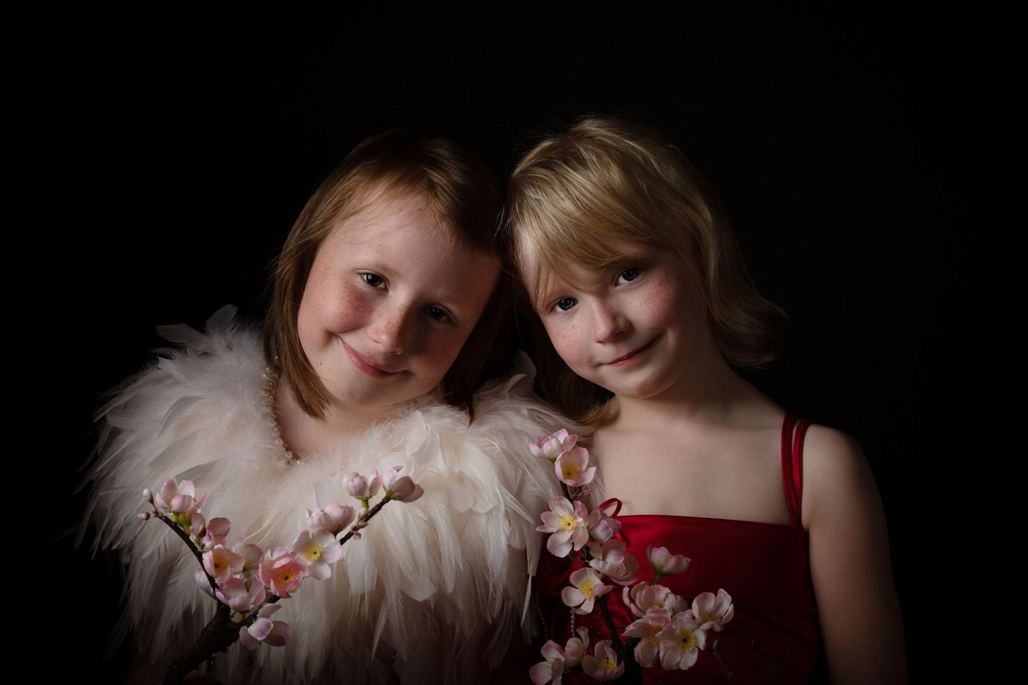 Dramatic studio portrait with white feathers and cherry blossoms against black background.