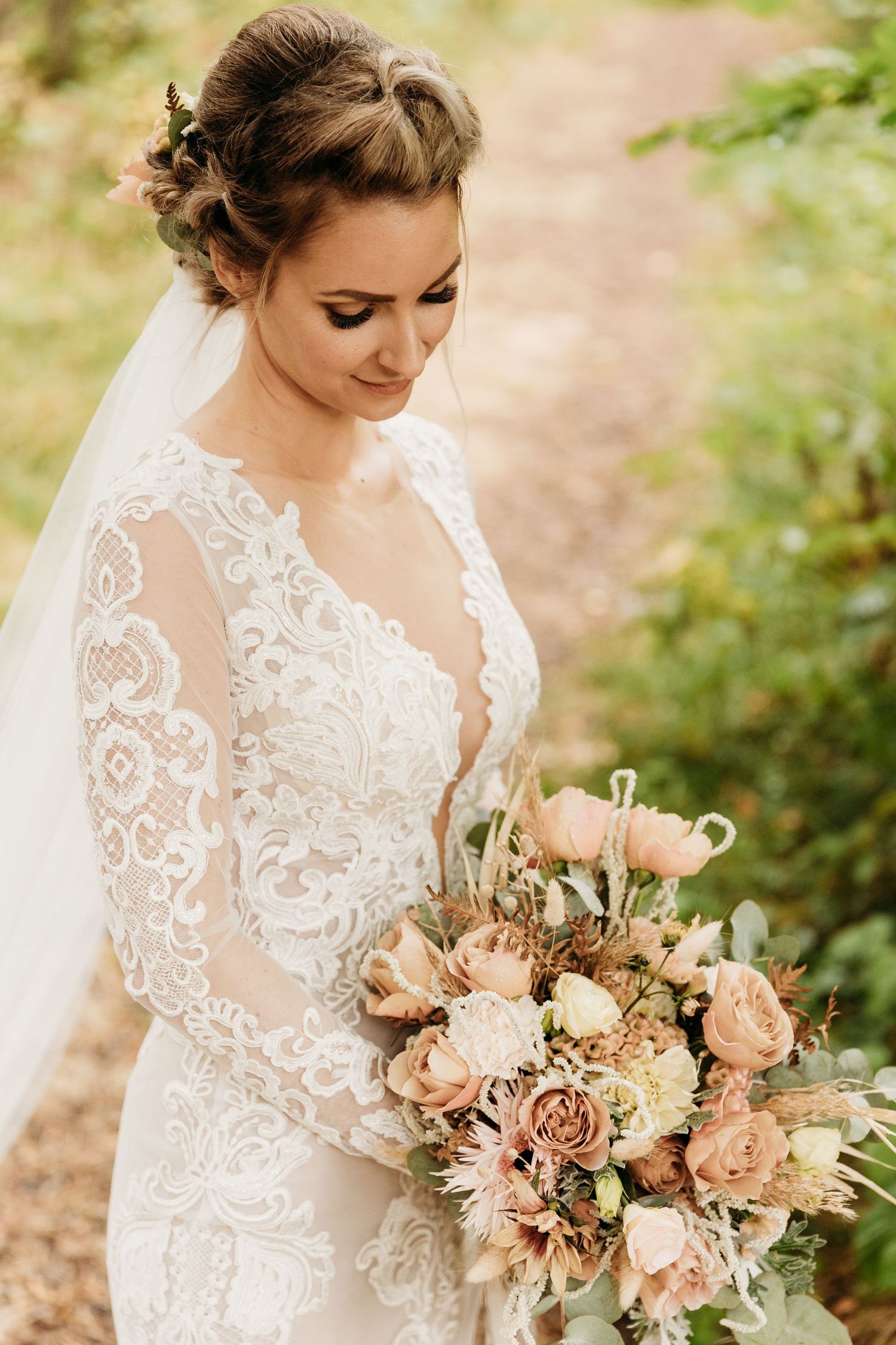 Close-up of a peach and cream wedding bouquet with roses and delicate lace dress details.