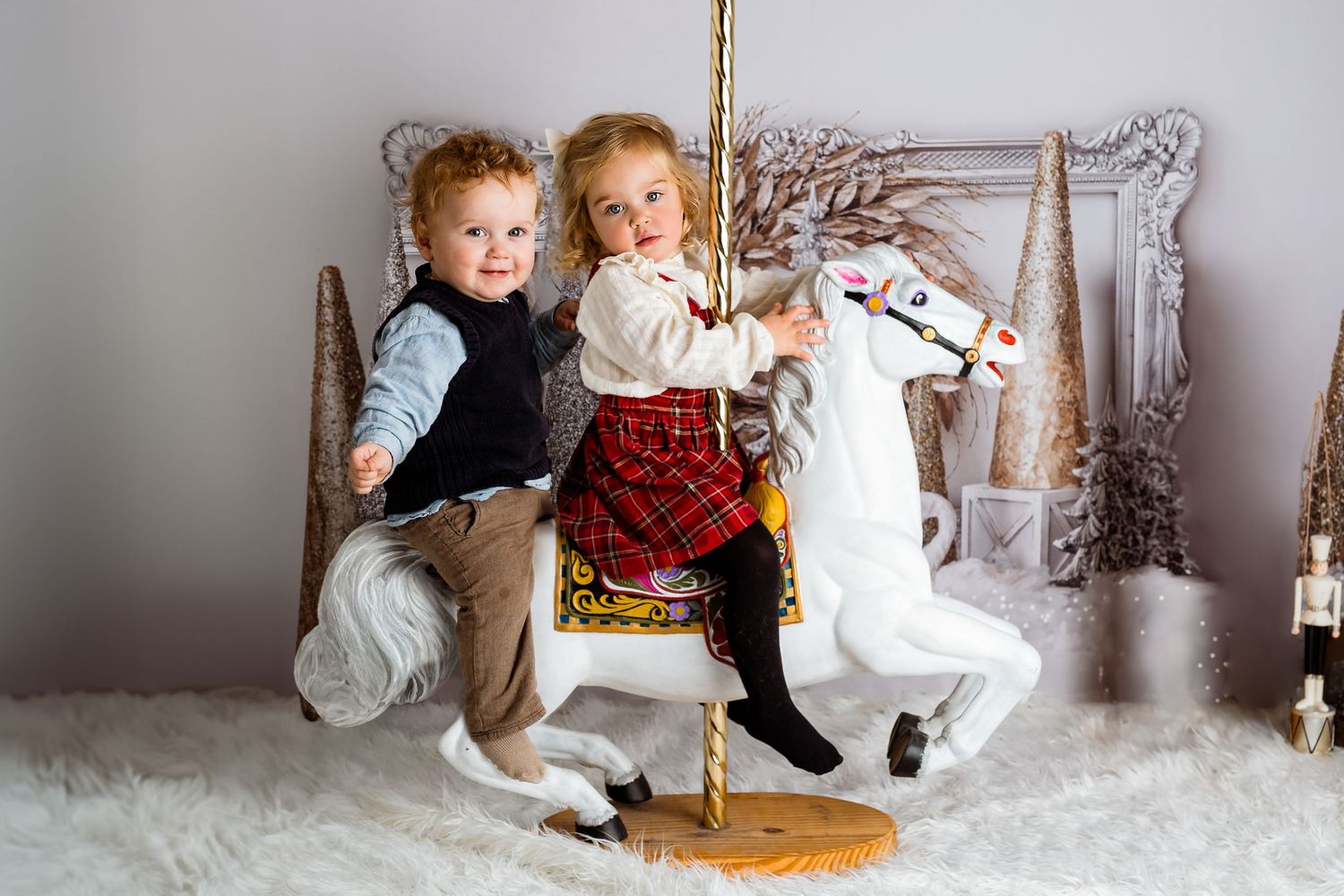 Winter themed photo session with children and decorative props on snowy white floor.