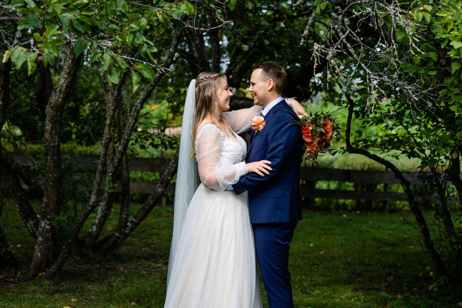 Newlyweds share an intimate moment in a lush garden setting.
