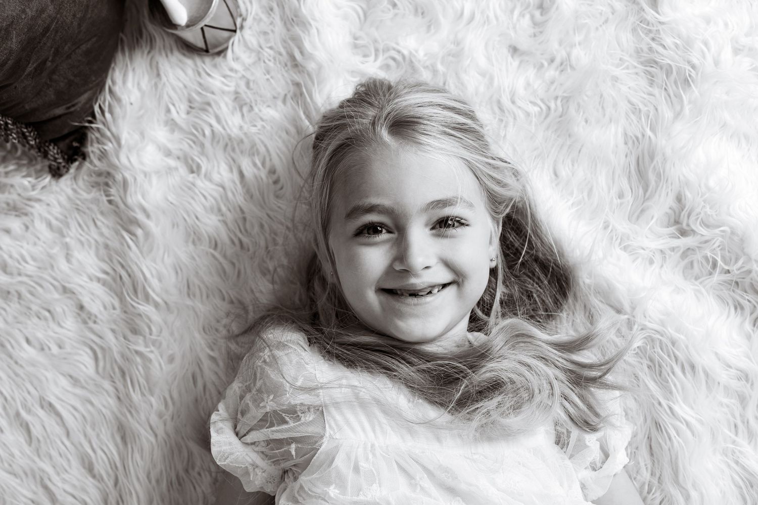 Close-up black and white portrait against white fluffy backdrop.