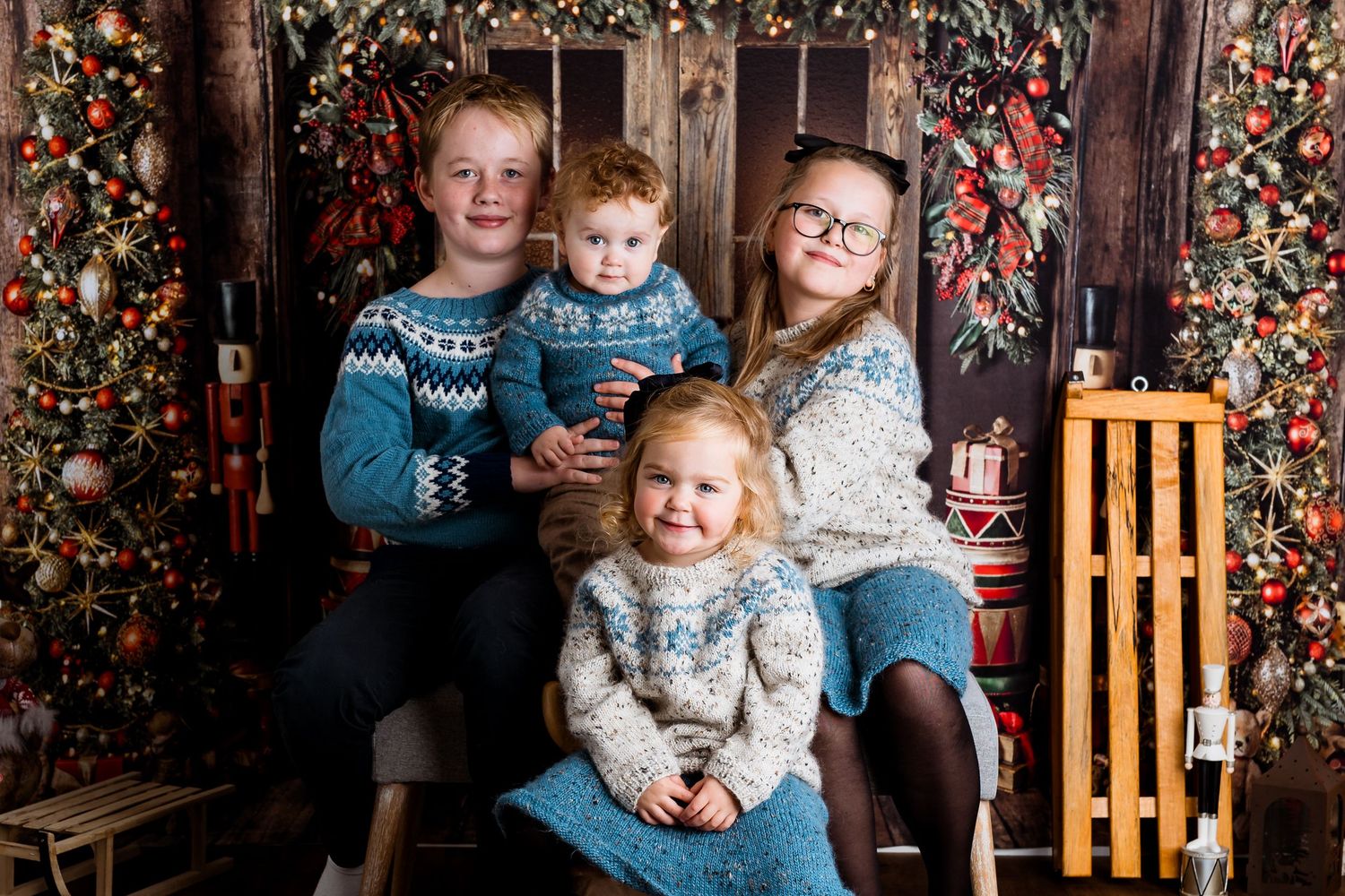 Holiday portrait session with children against decorated Christmas backdrop.
