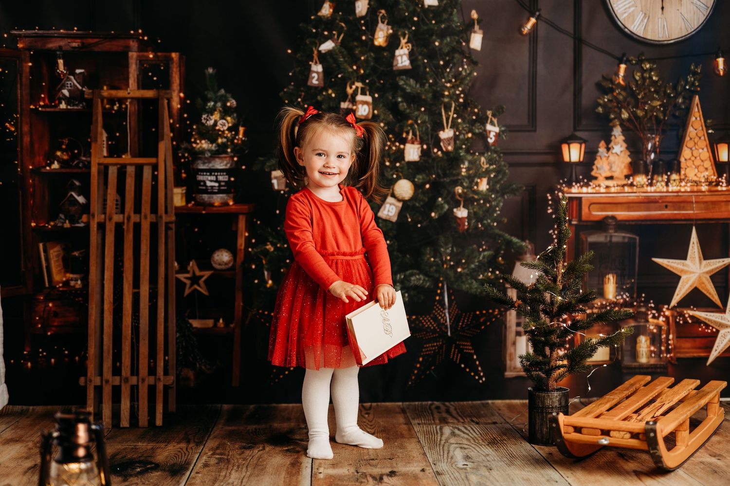 Holiday photo backdrop with illuminated Christmas tree and wooden decorative elements.