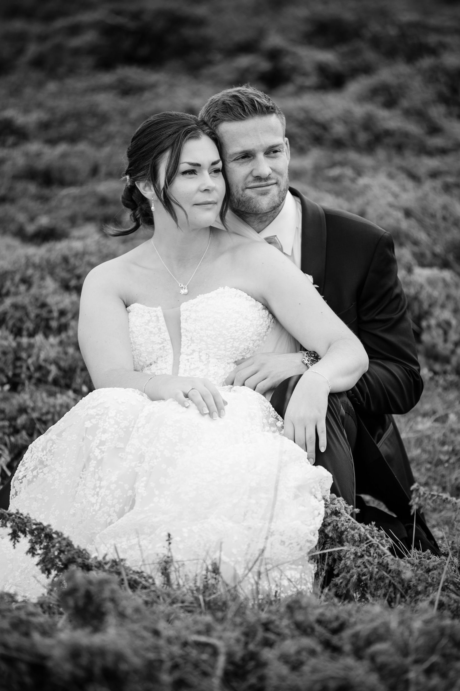 Black and white portrait of couple resting together in natural outdoor setting.