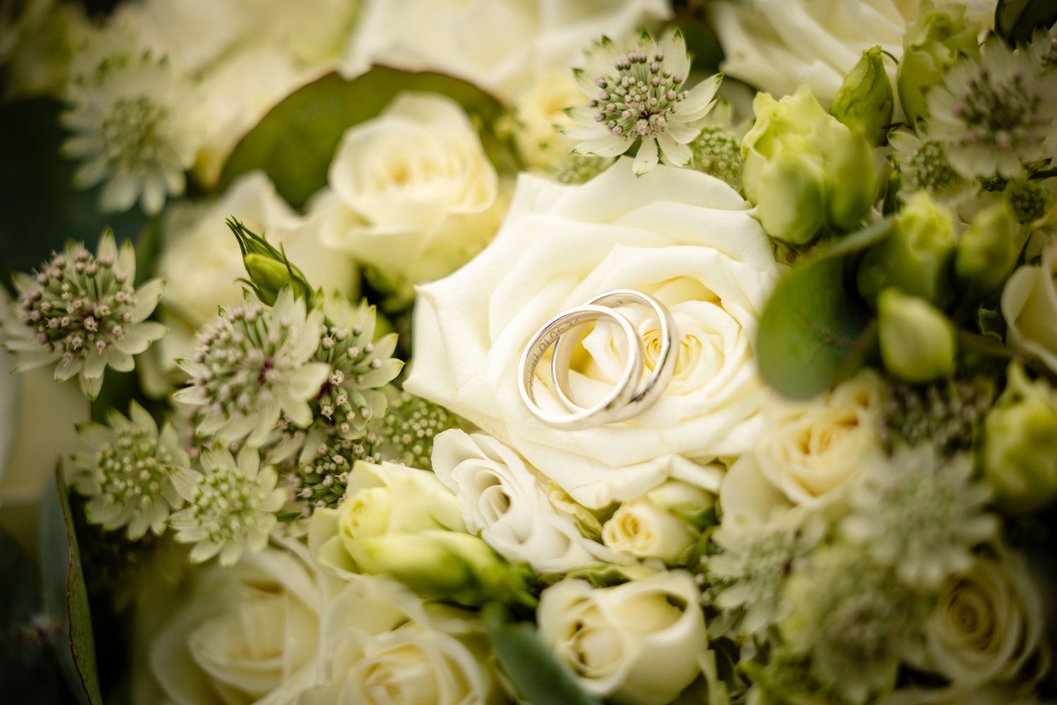 Close-up of an elegant white wedding bouquet with roses and delicate floral arrangements.