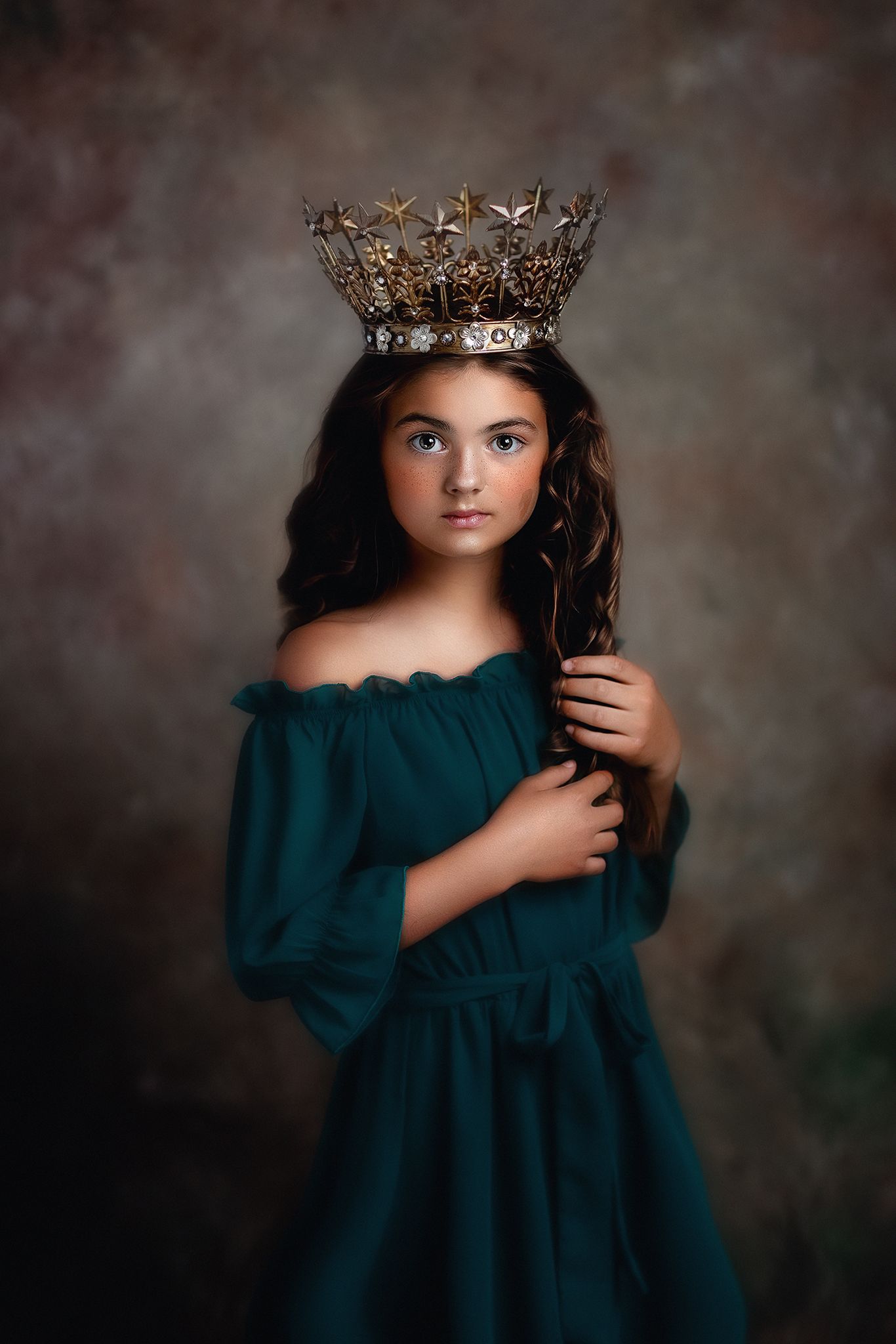 Artistic portrait in teal dress with crown against dark background.
