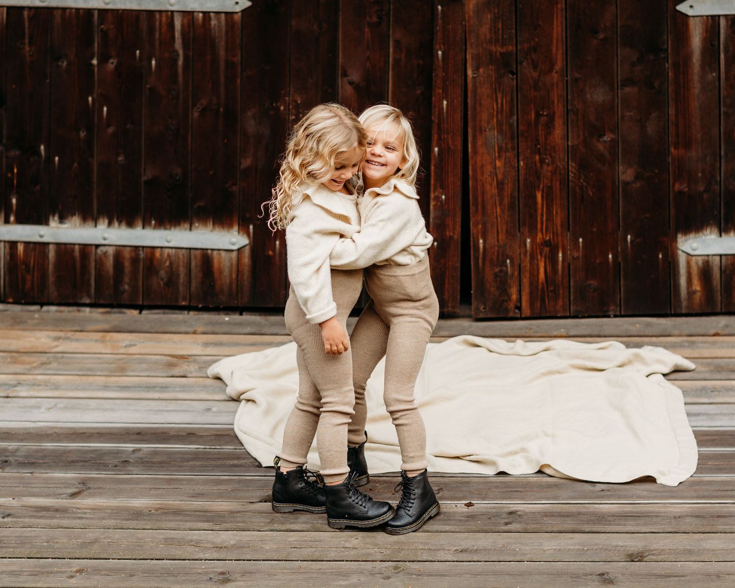 People sitting together on wooden deck wearing cream colored clothing.