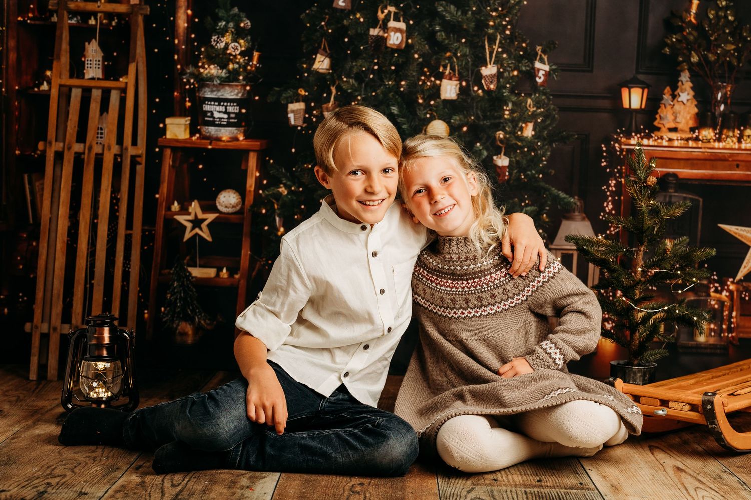 Cozy Christmas family photoshoot with decorated tree and wooden backdrop.