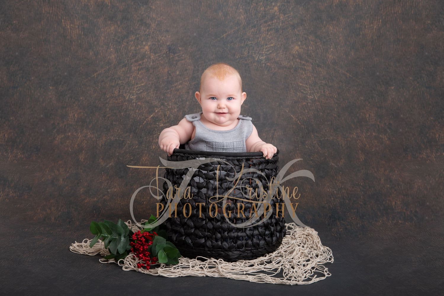 Baby posed in vintage-style setting with lace and roses on dark background.