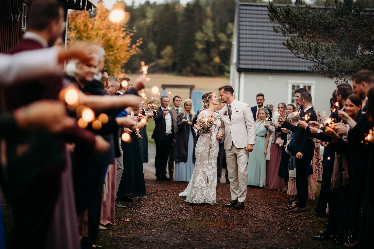 Wedding guests form a sparkler exit tunnel at dusk creating a magical atmosphere.