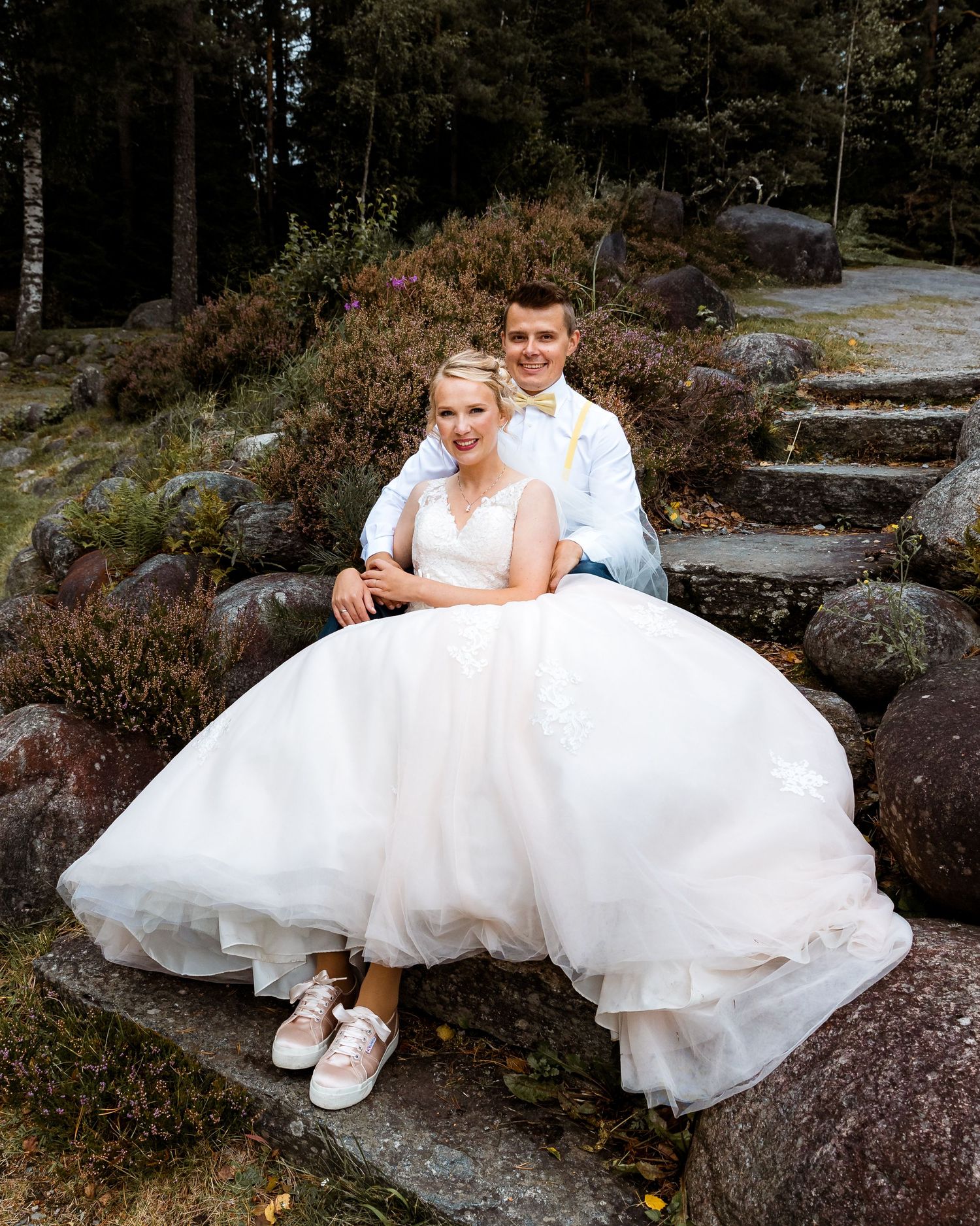 Wedding couple seated on stone steps with bride's dress flowing dramatically.