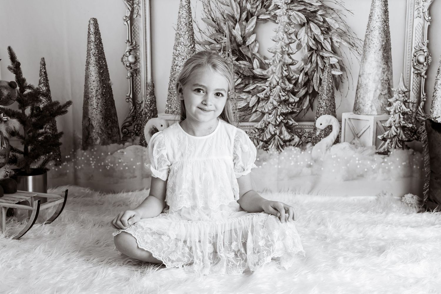 Winter wonderland studio portrait with decorative trees and snow-covered setting.
