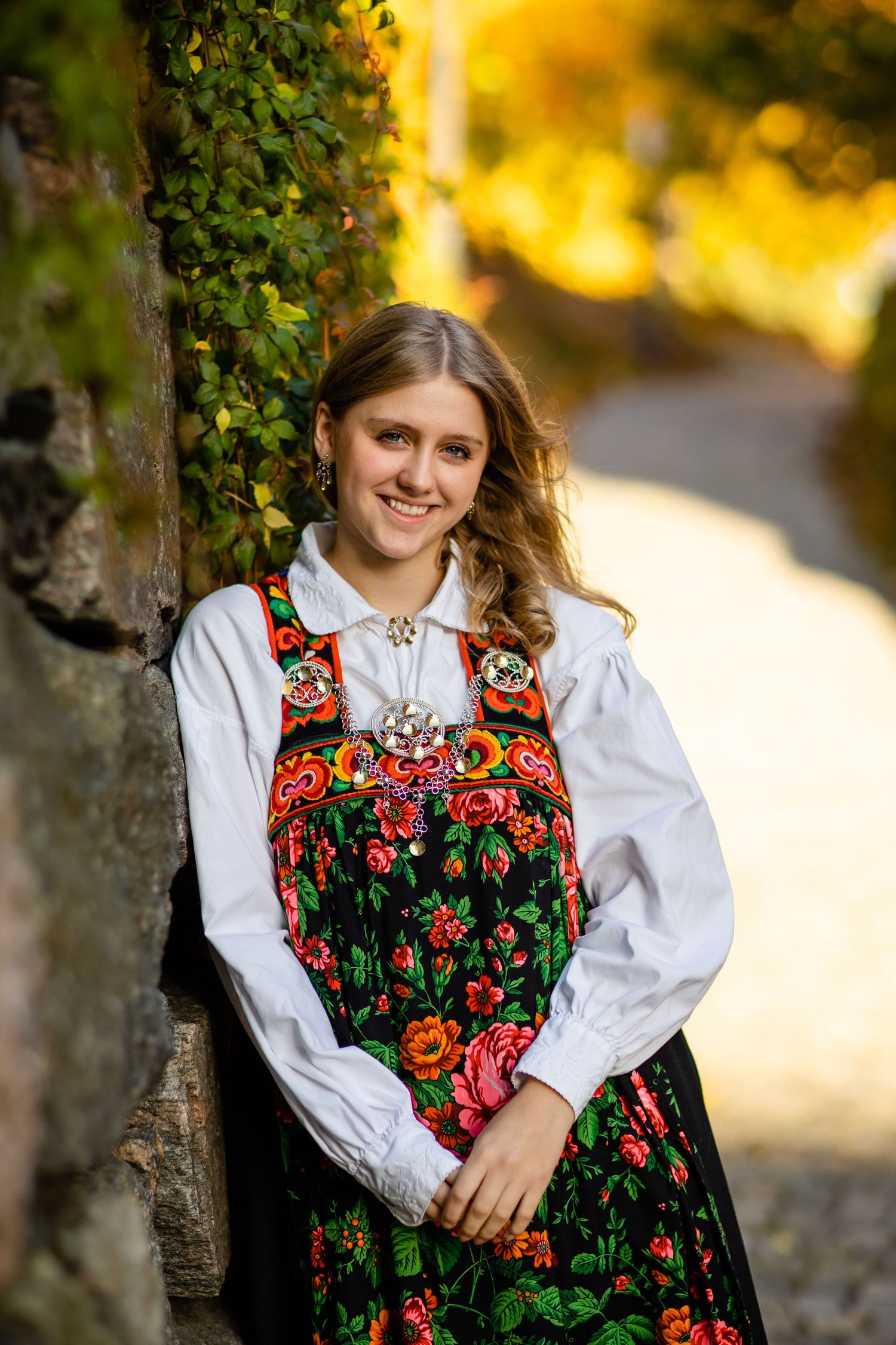 Traditional folk dress with colorful floral embroidery photographed in golden sunlight.