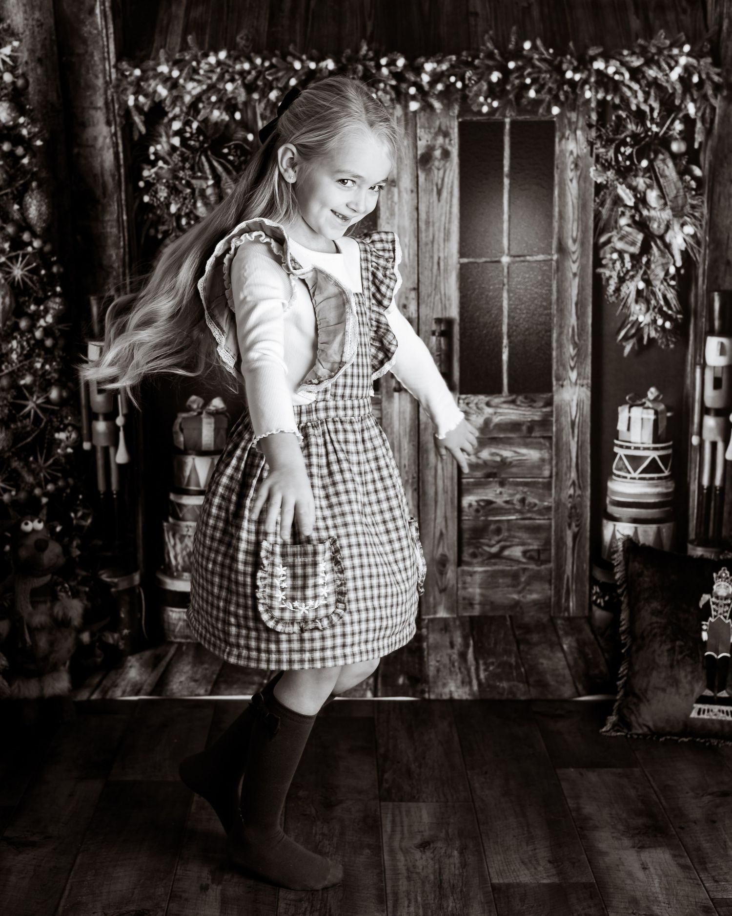 Black and white portrait series showing playful poses against a rustic wooden backdrop with holiday decor.