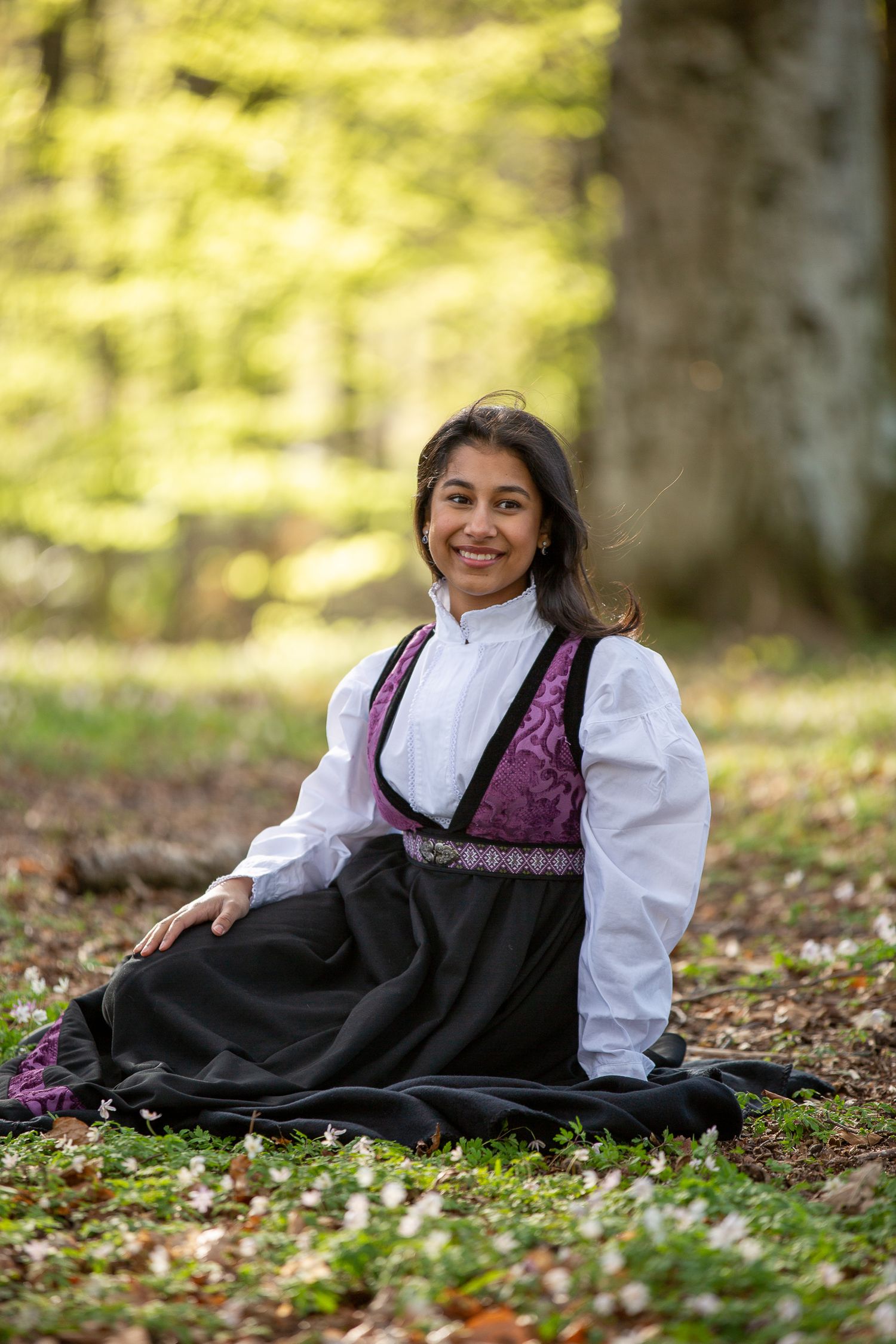 Joyful outdoor portraits in traditional Nordic dress among spring forest flowers.