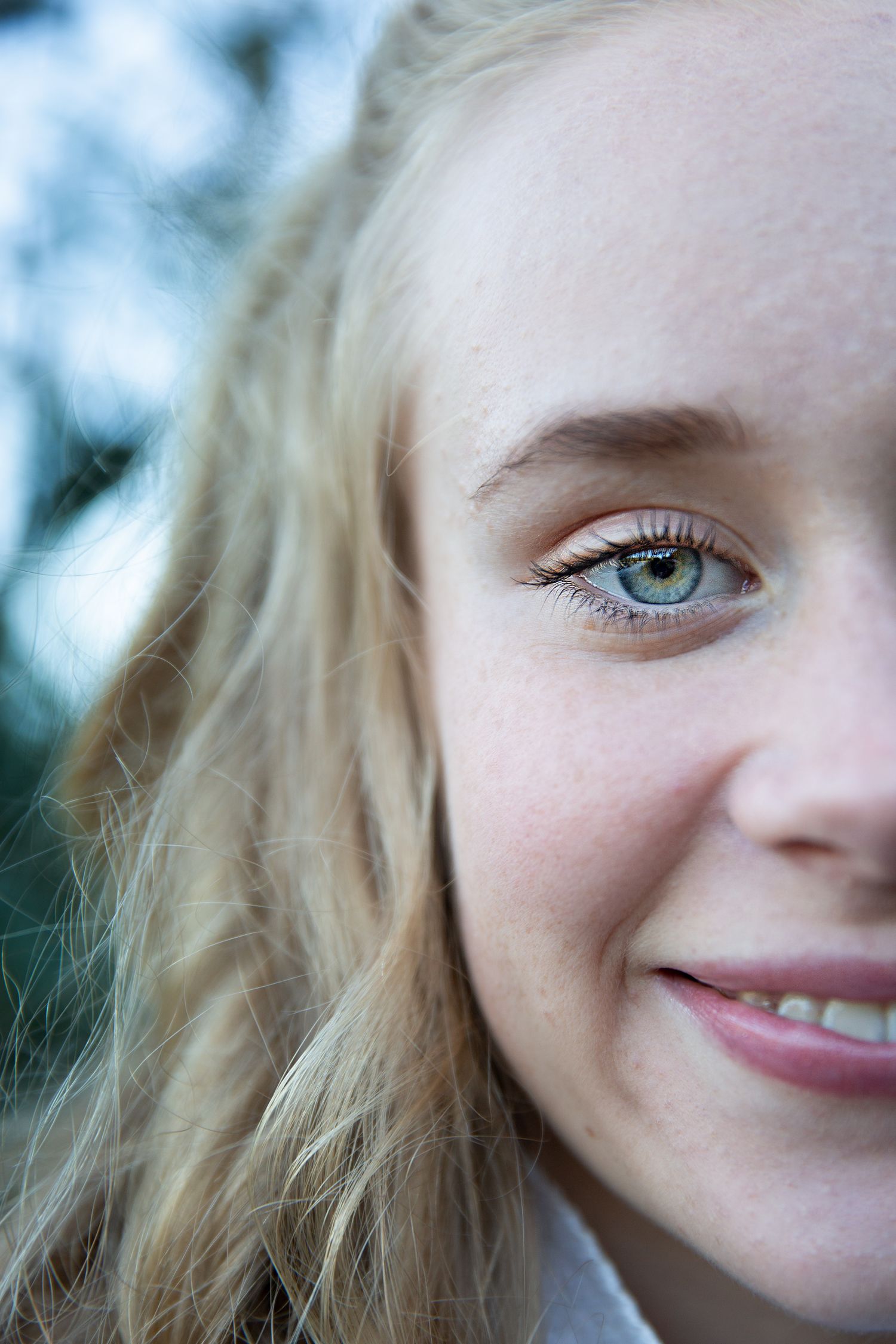 A close-up portrait showing bright blue eyes and a gentle smile against a soft blurred background.