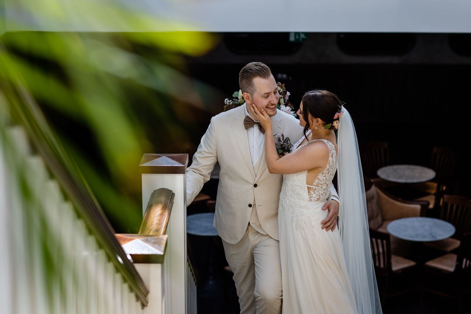 A couple shares a tender moment on their wedding day in an outdoor tropical setting.