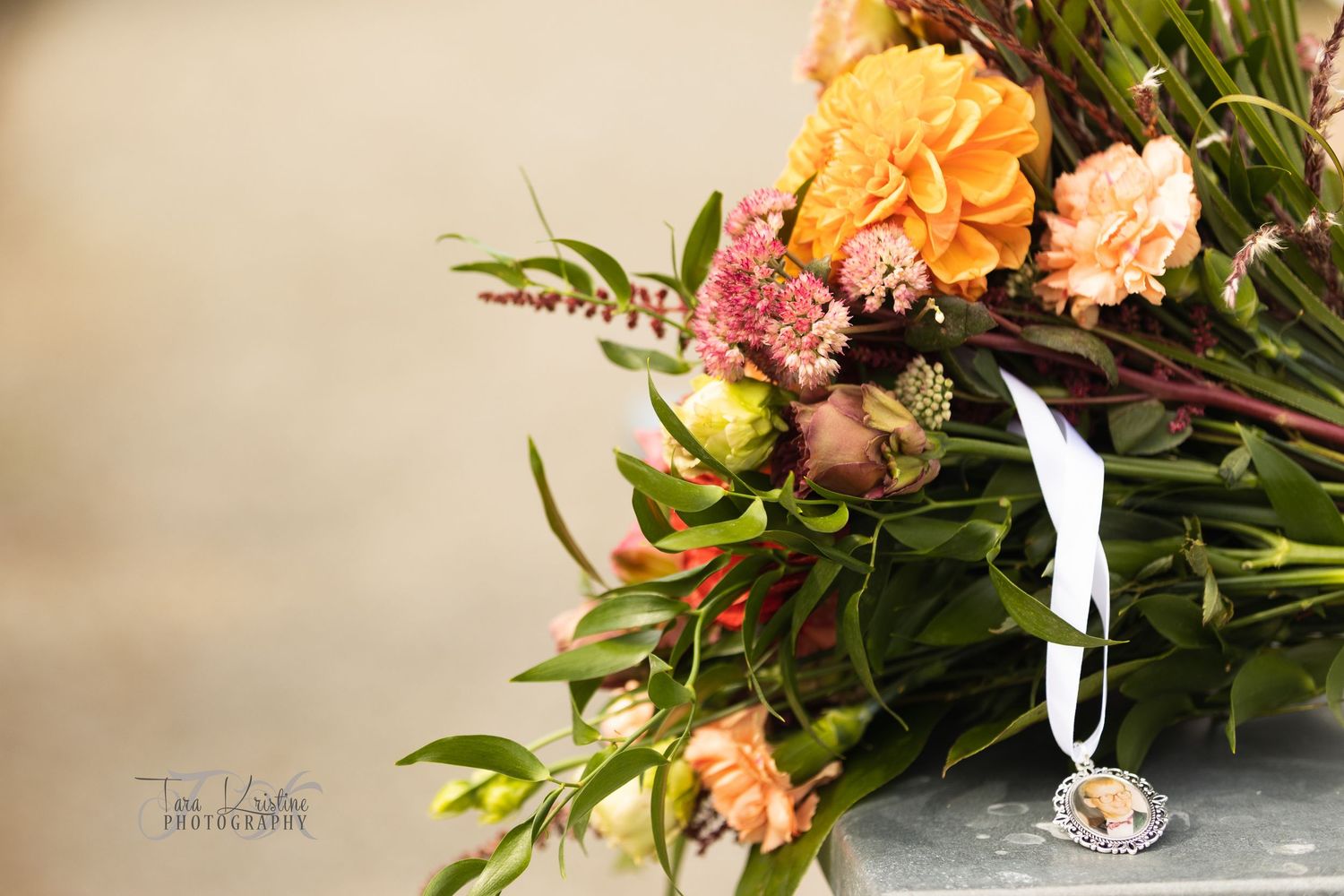 Vibrant orange and pink floral wedding bouquet arrangement against neutral background.