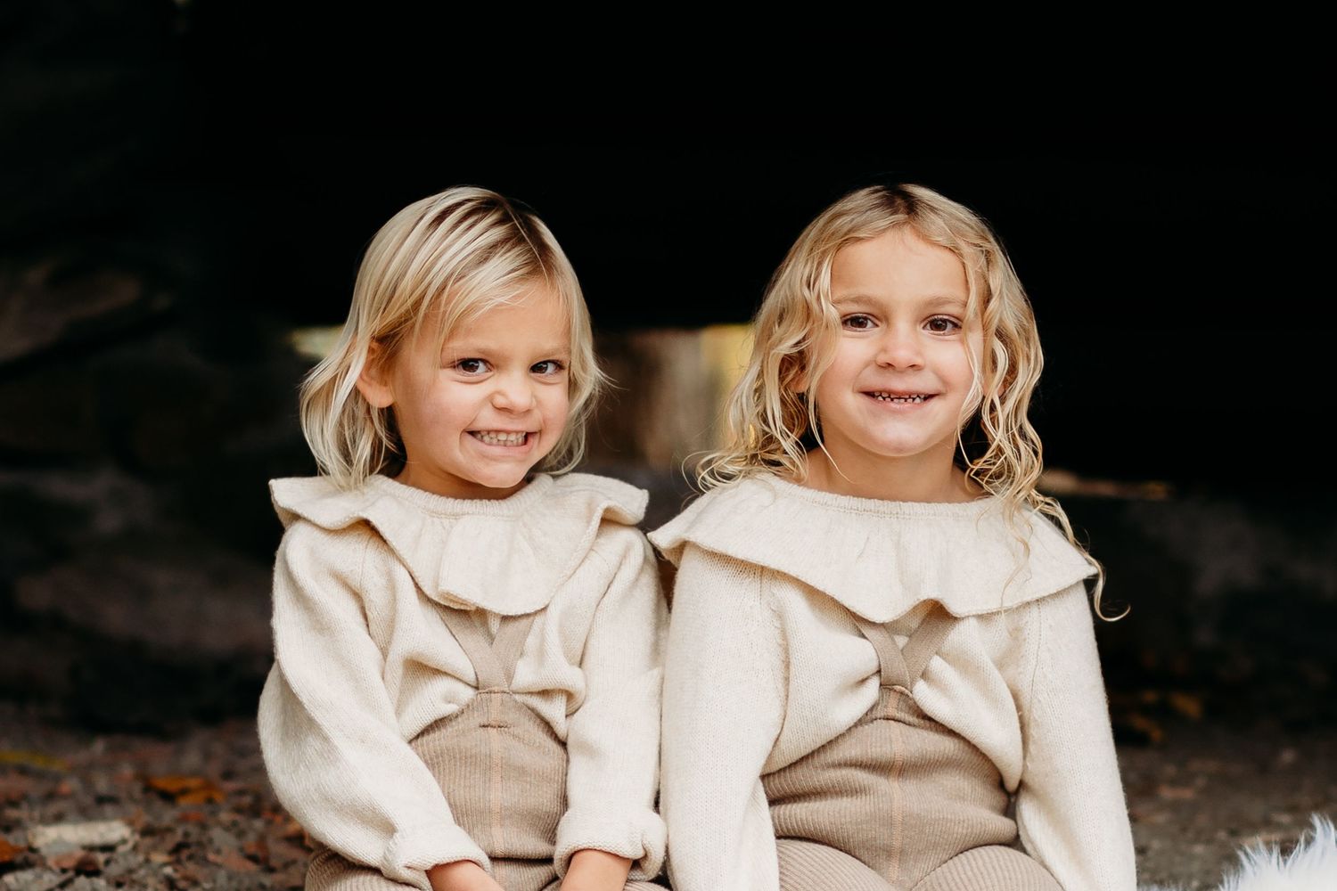 Two people in matching cream sweaters sitting together and smiling.