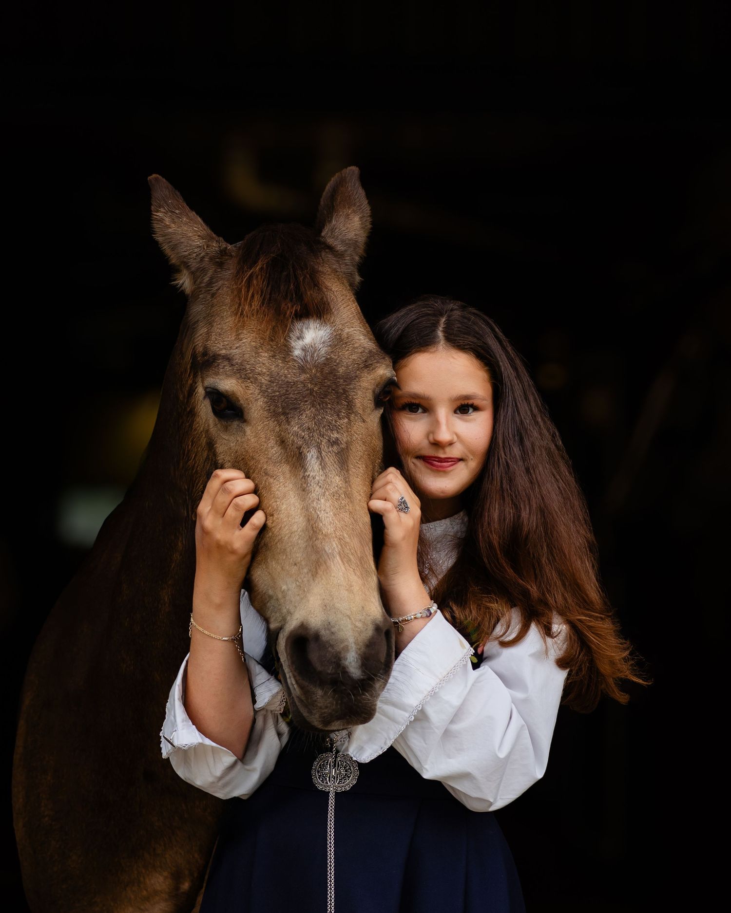 A series of intimate portraits showing tender moments between a person in white clothing and a brown horse against a dark background.