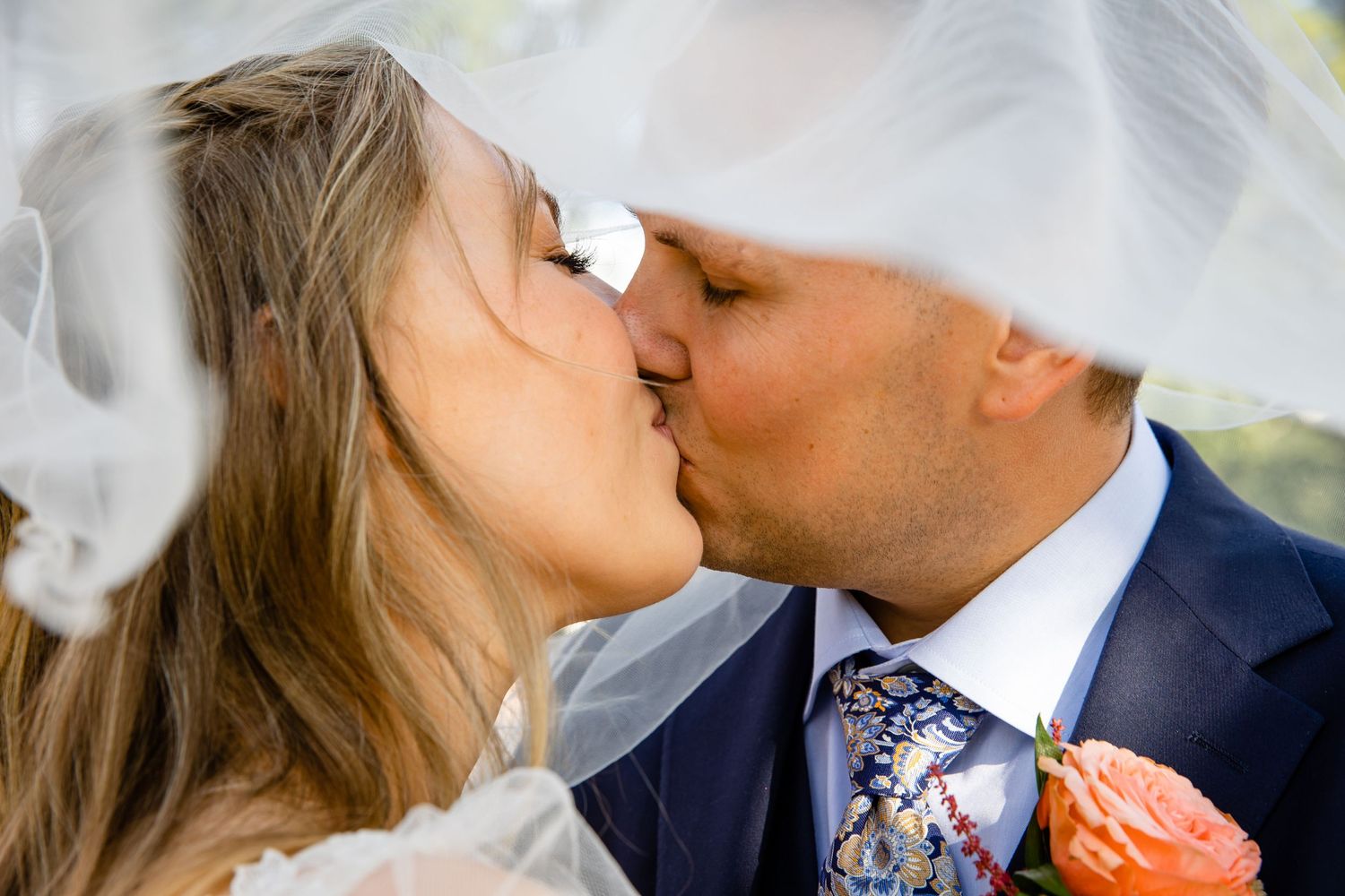 Romantic wedding kiss captured through flowing white veil.